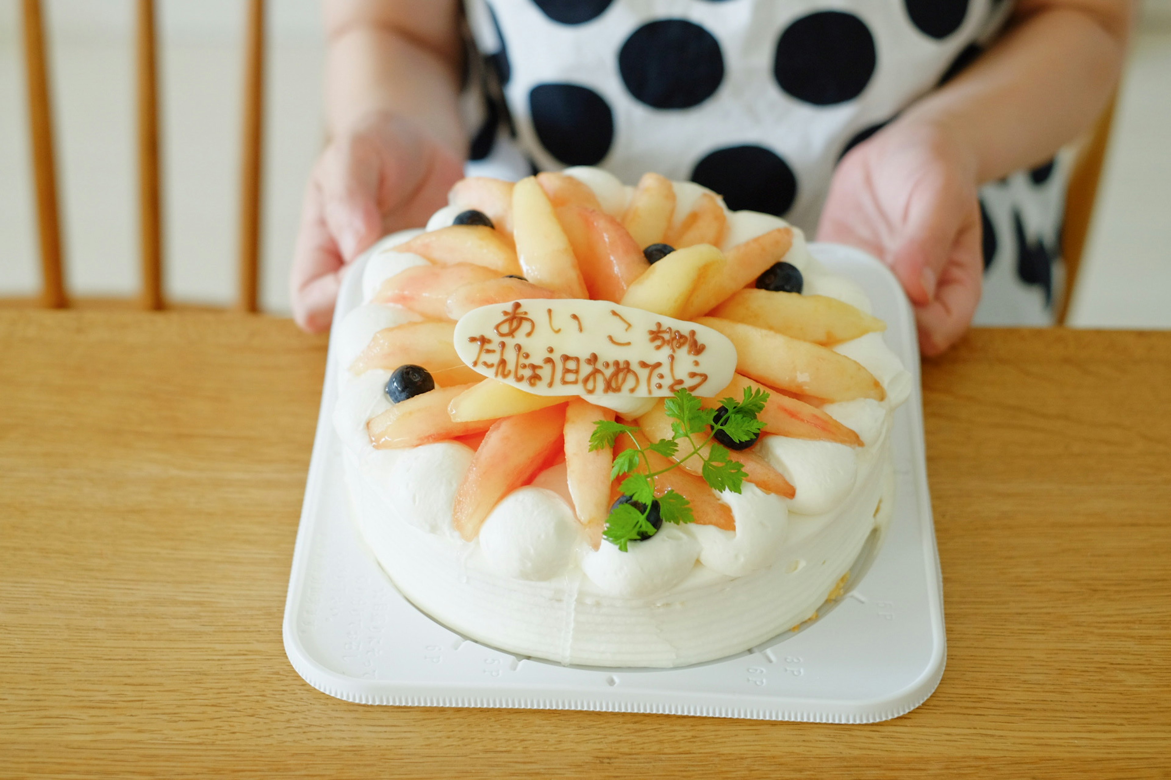 Person holding a fruit-decorated cake