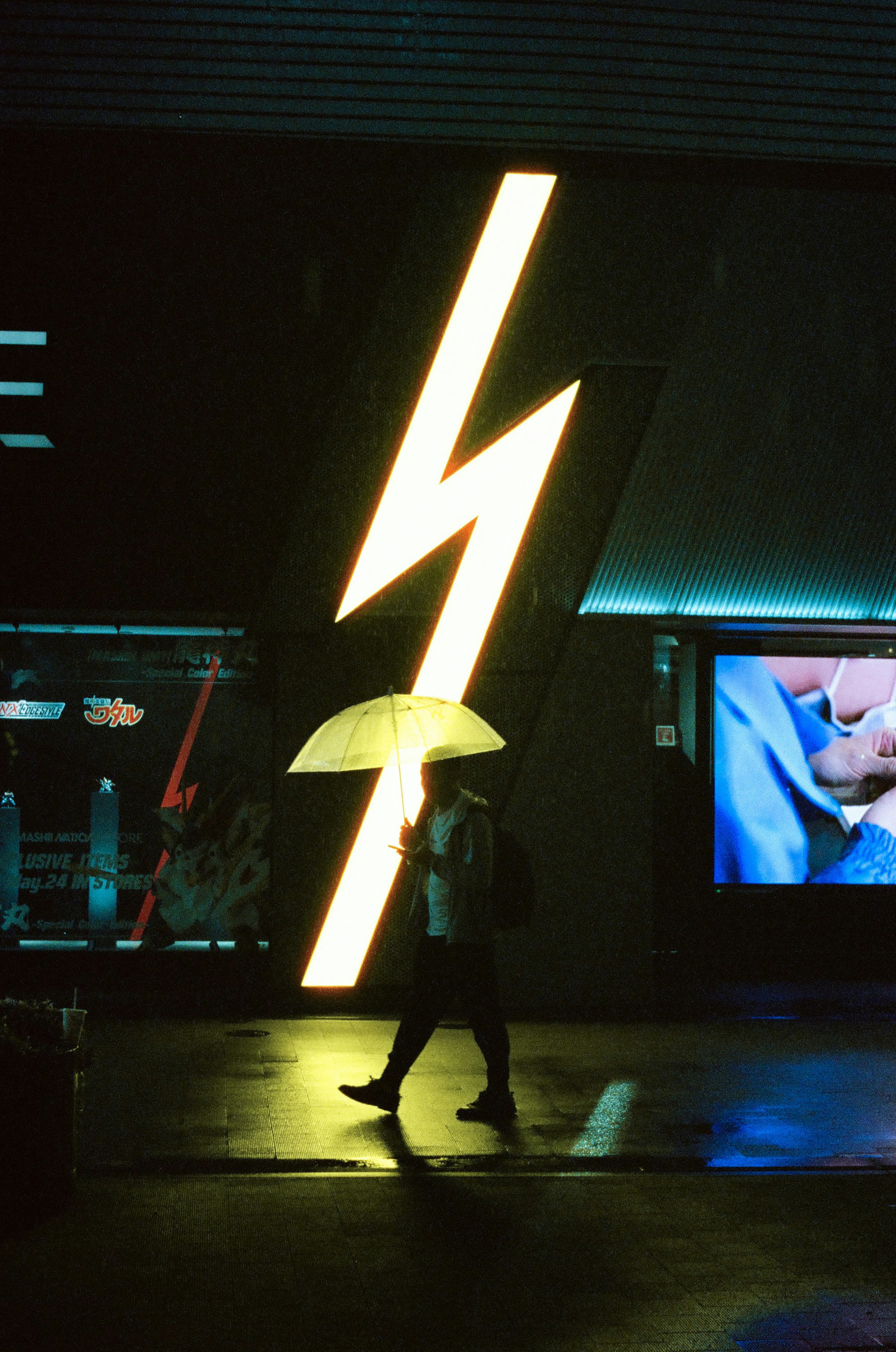 Person geht mit einem Regenschirm vor einem Neonblitzschild