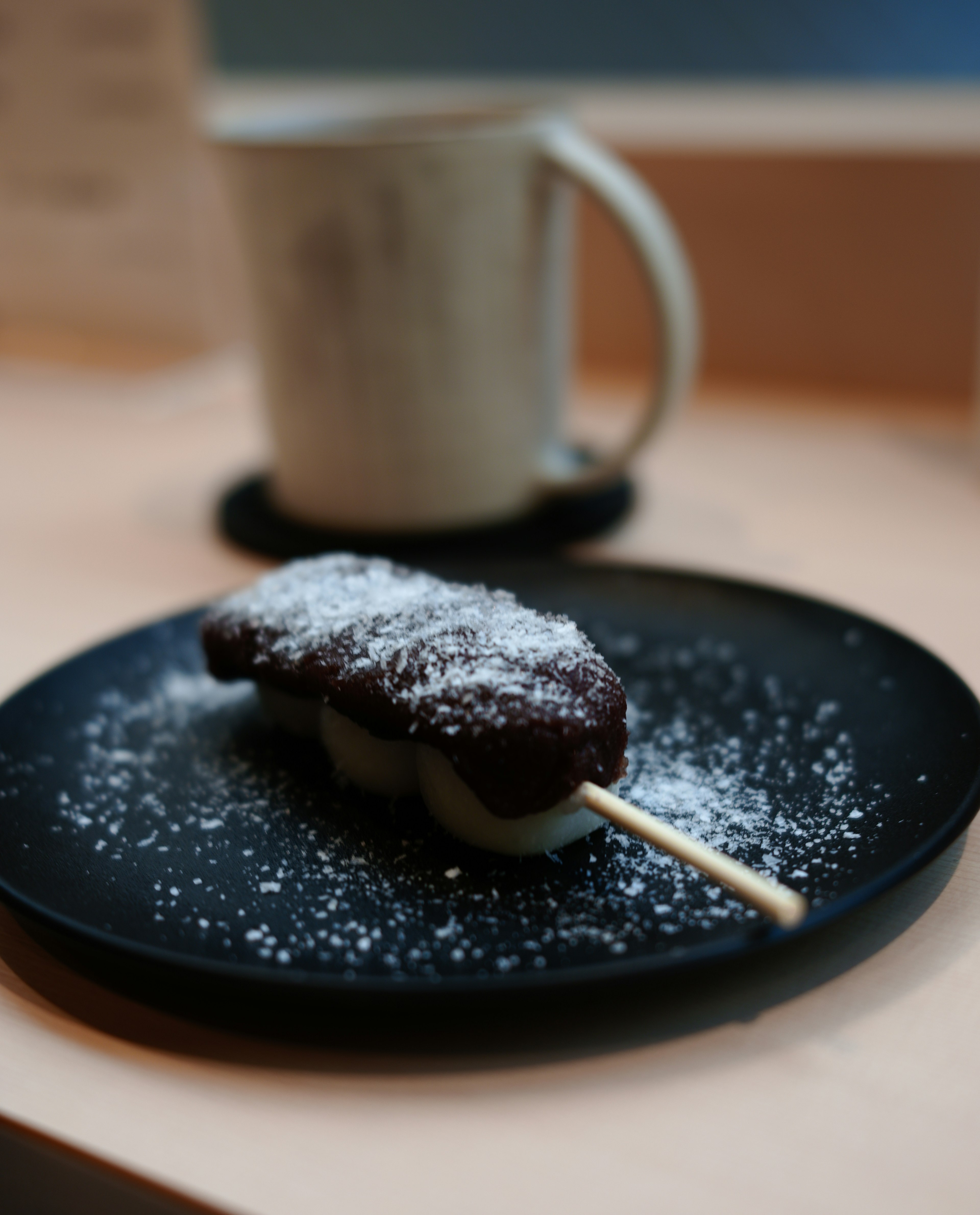 Un postre en un plato negro espolvoreado con azúcar glas