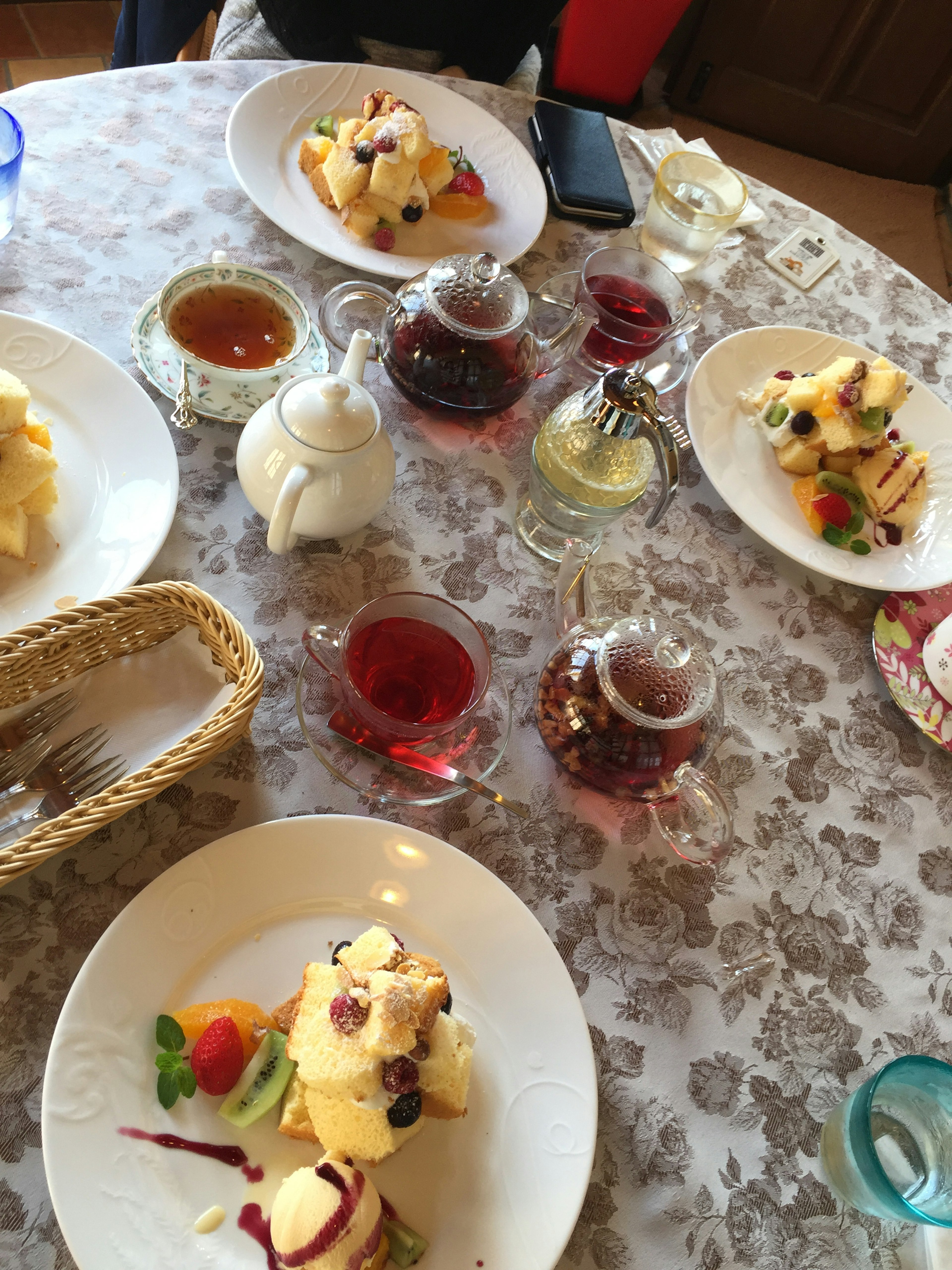 Postre y juego de té dispuestos en una mesa con dulces cubiertos de frutas y crema