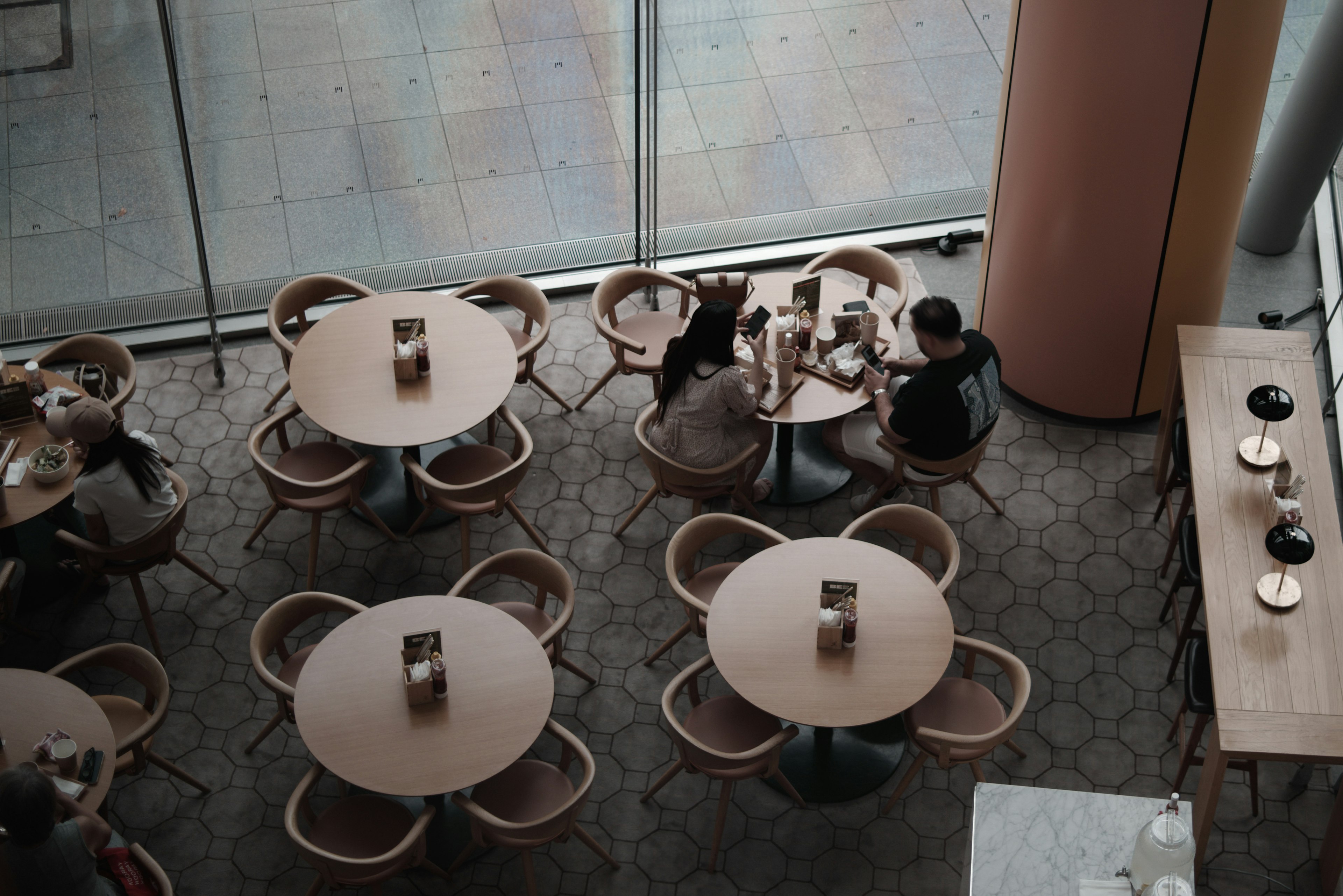 Vista aérea de una cafetería con mesas redondas y sillas de madera