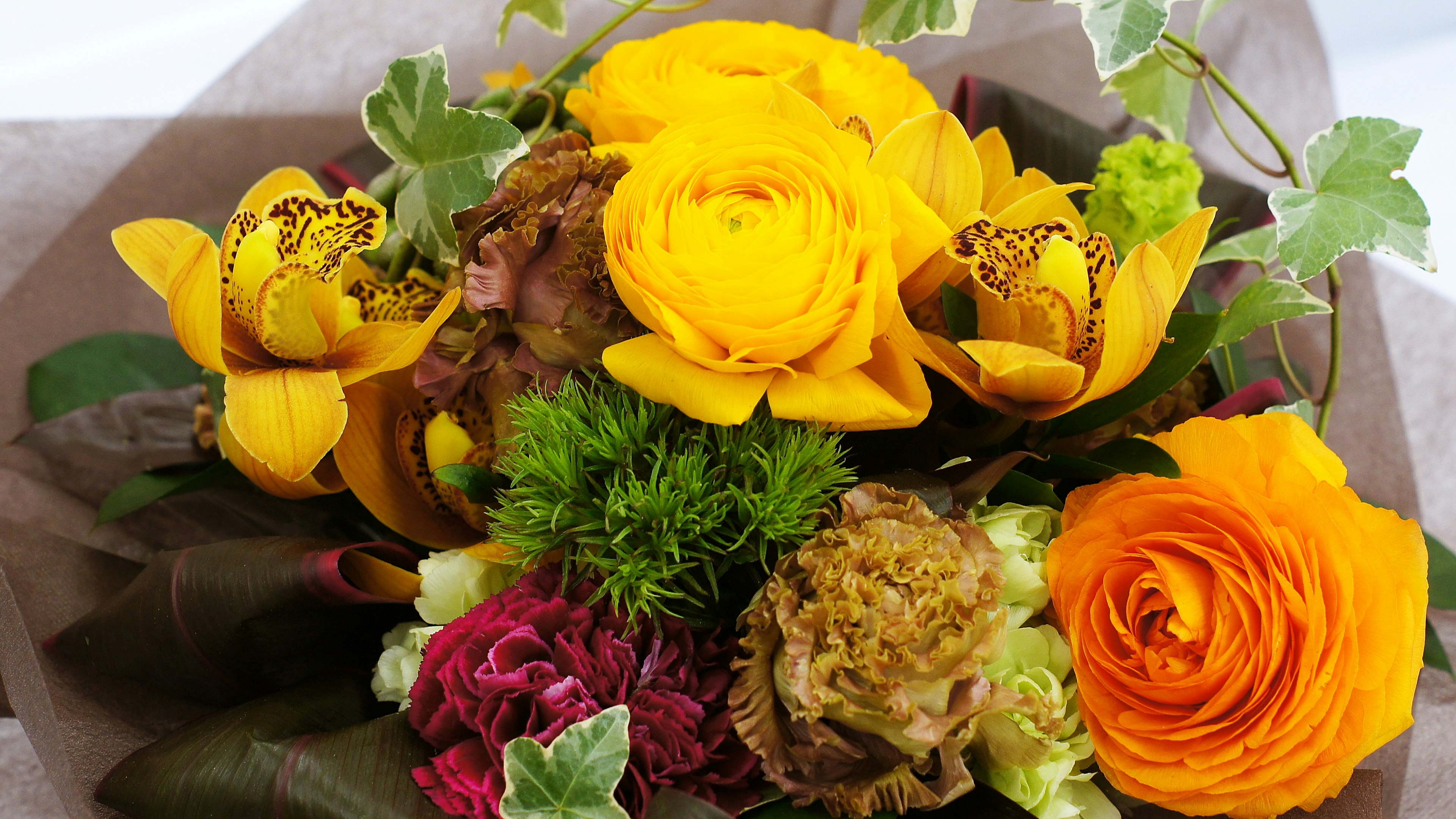 Ramo con rosas amarillas y orquídeas combinadas con hojas verdes y otras flores