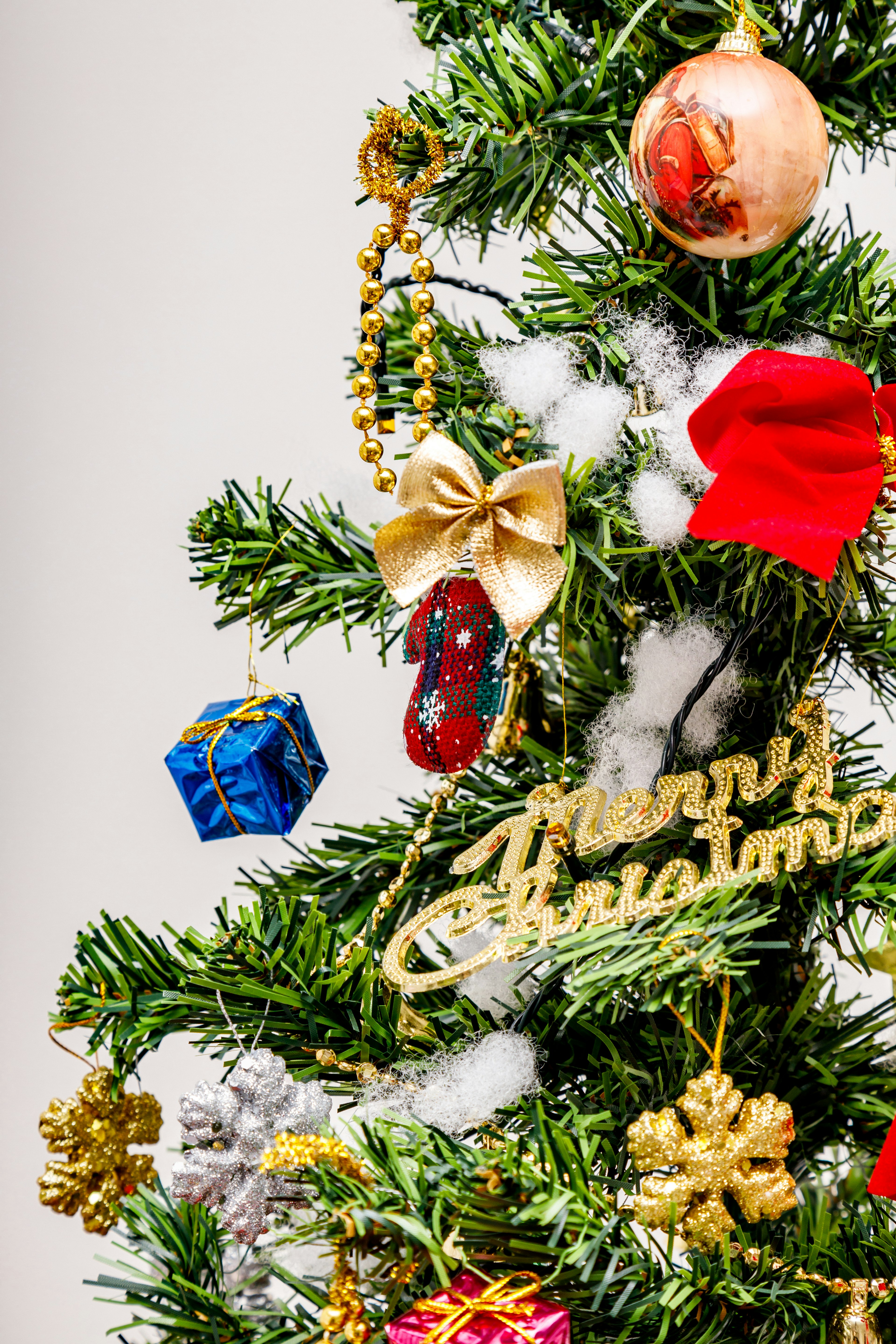 A decorated Christmas tree branch featuring red bows gold ornaments and a blue gift box