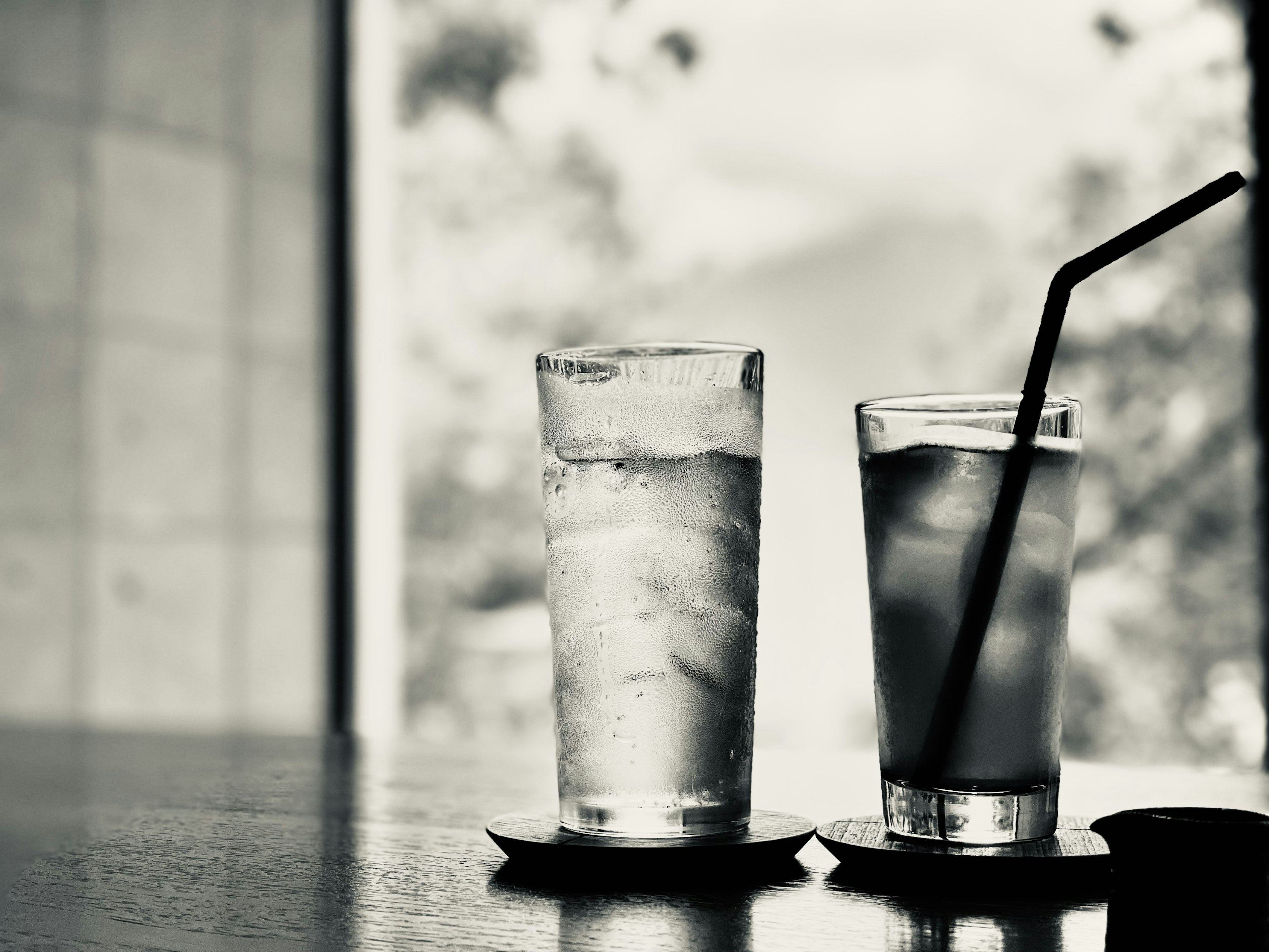 Table with a glass of iced water and a drink with a straw