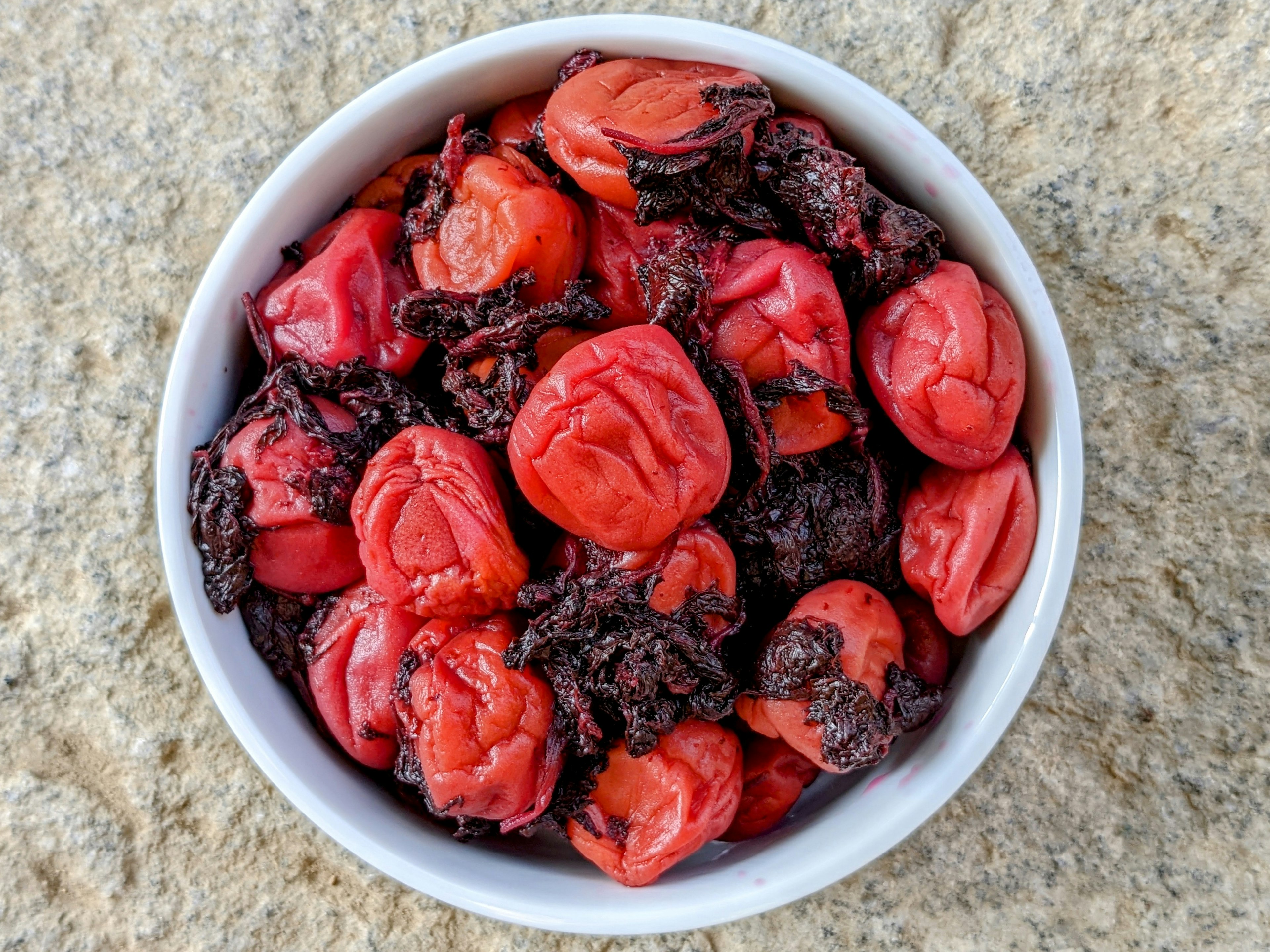 Schüssel mit roten Umeboshi-Pflaumen und dunklem Seetang