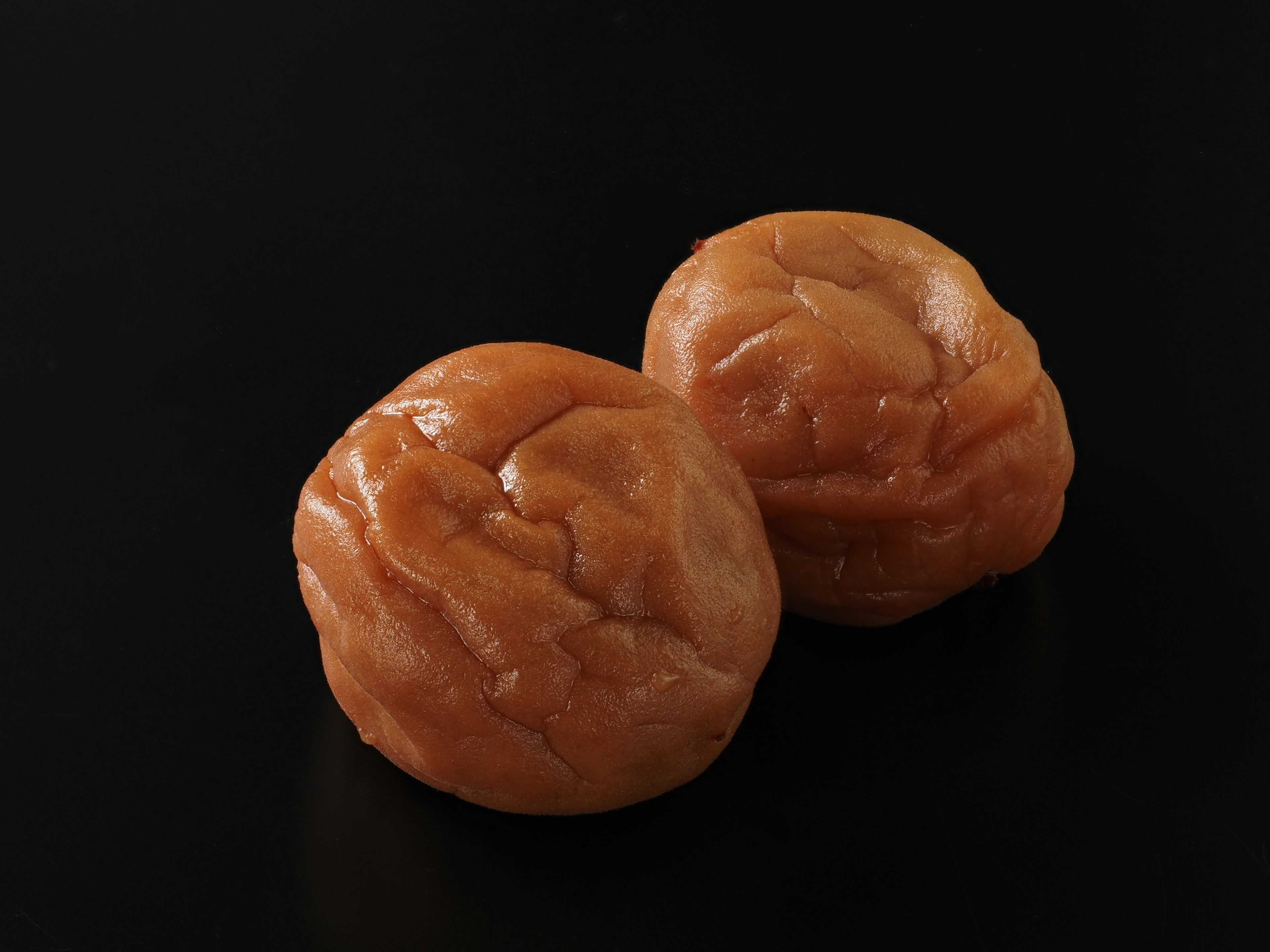 Hai quả umeboshi đặt trên nền đen