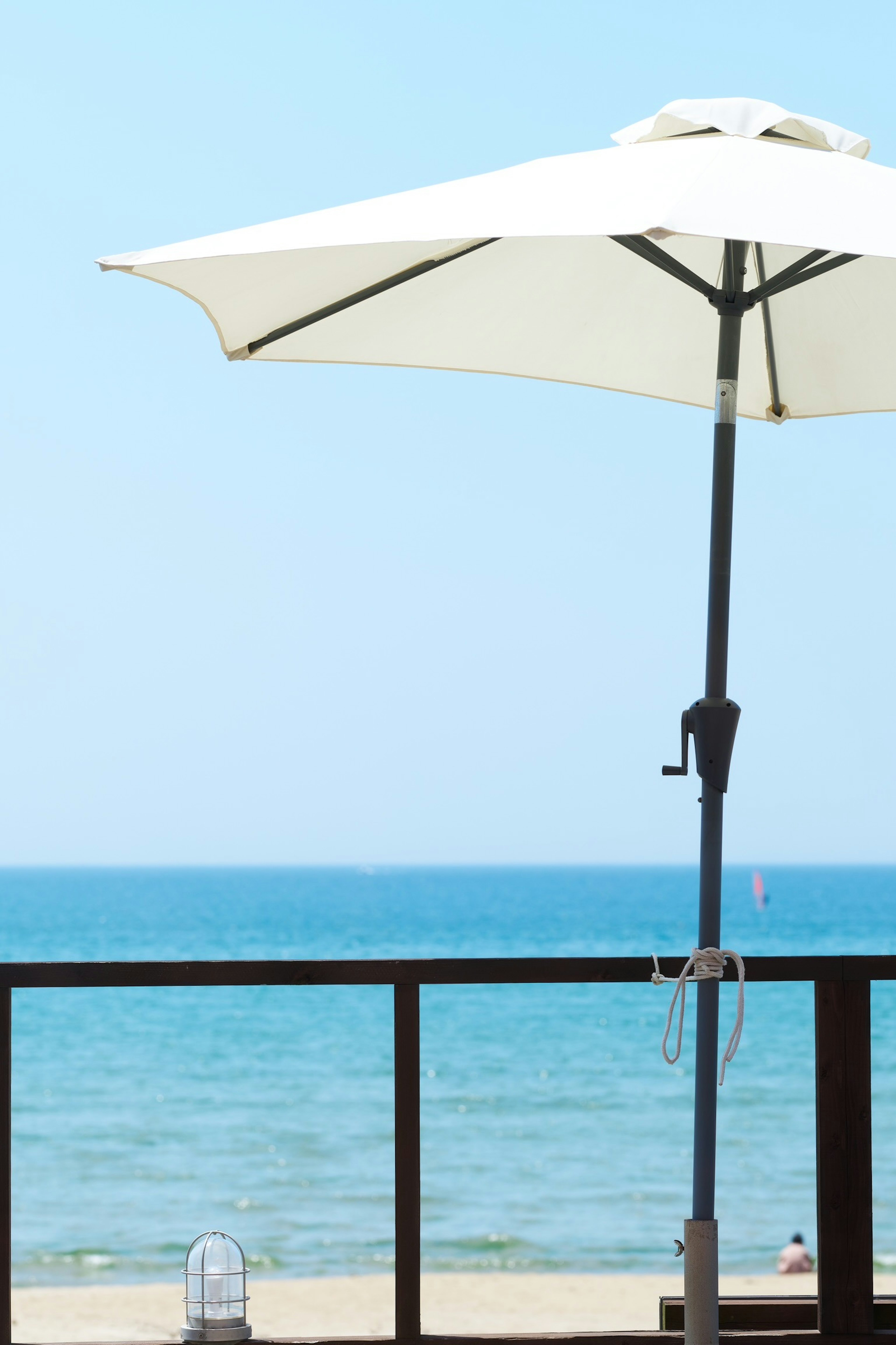 Scène de plage avec un parasol blanc et un océan bleu