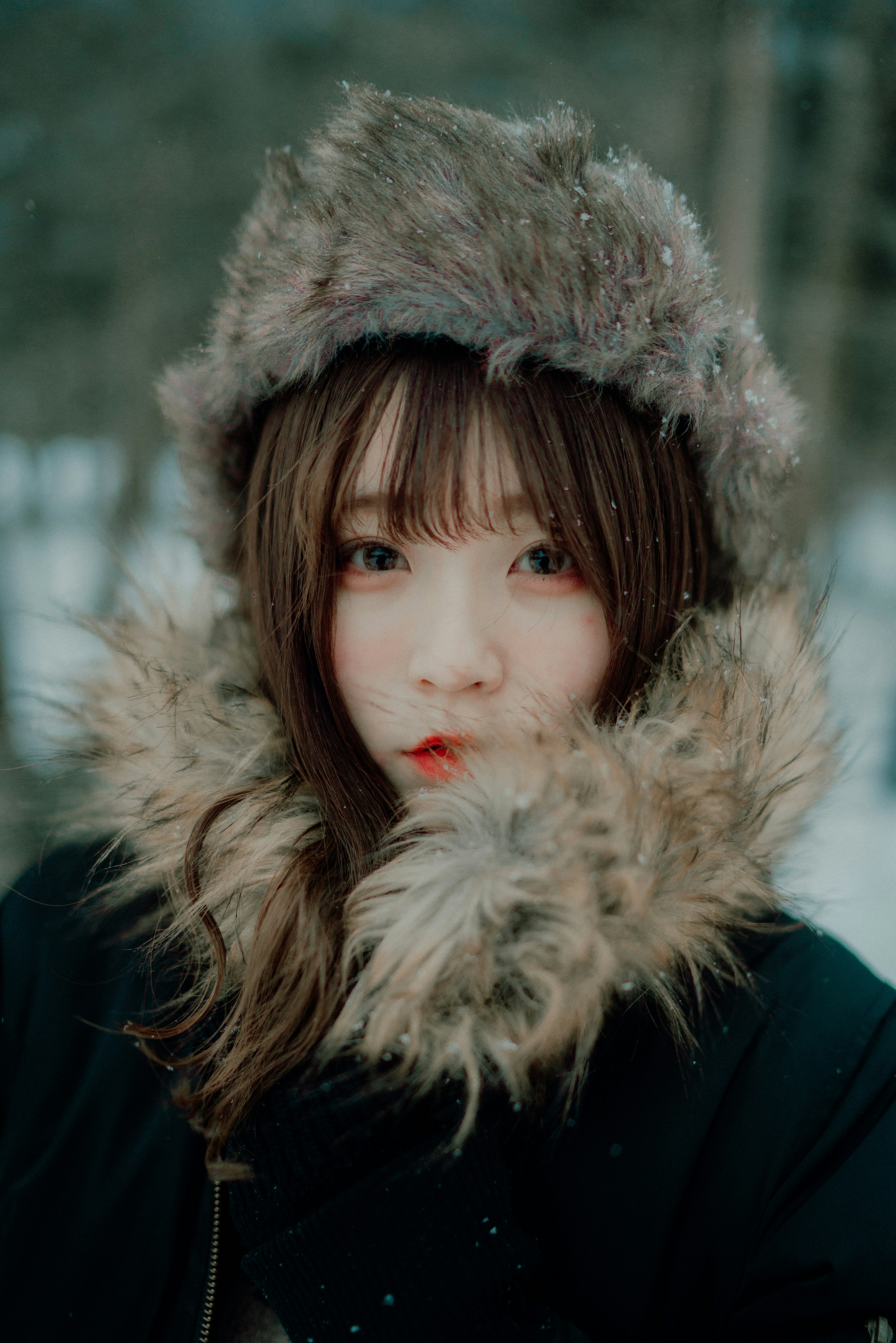 Una donna con un cappotto invernale e un cappello di pelliccia guarda in camera