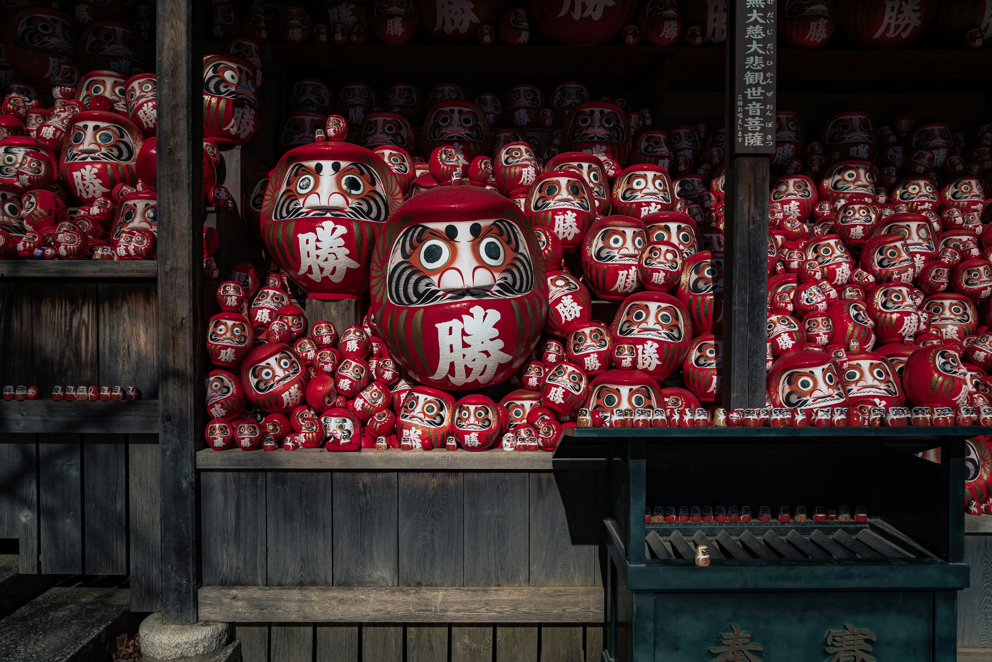 Eine Ausstellung von zahlreichen roten Daruma-Puppen mit einer großen vorne