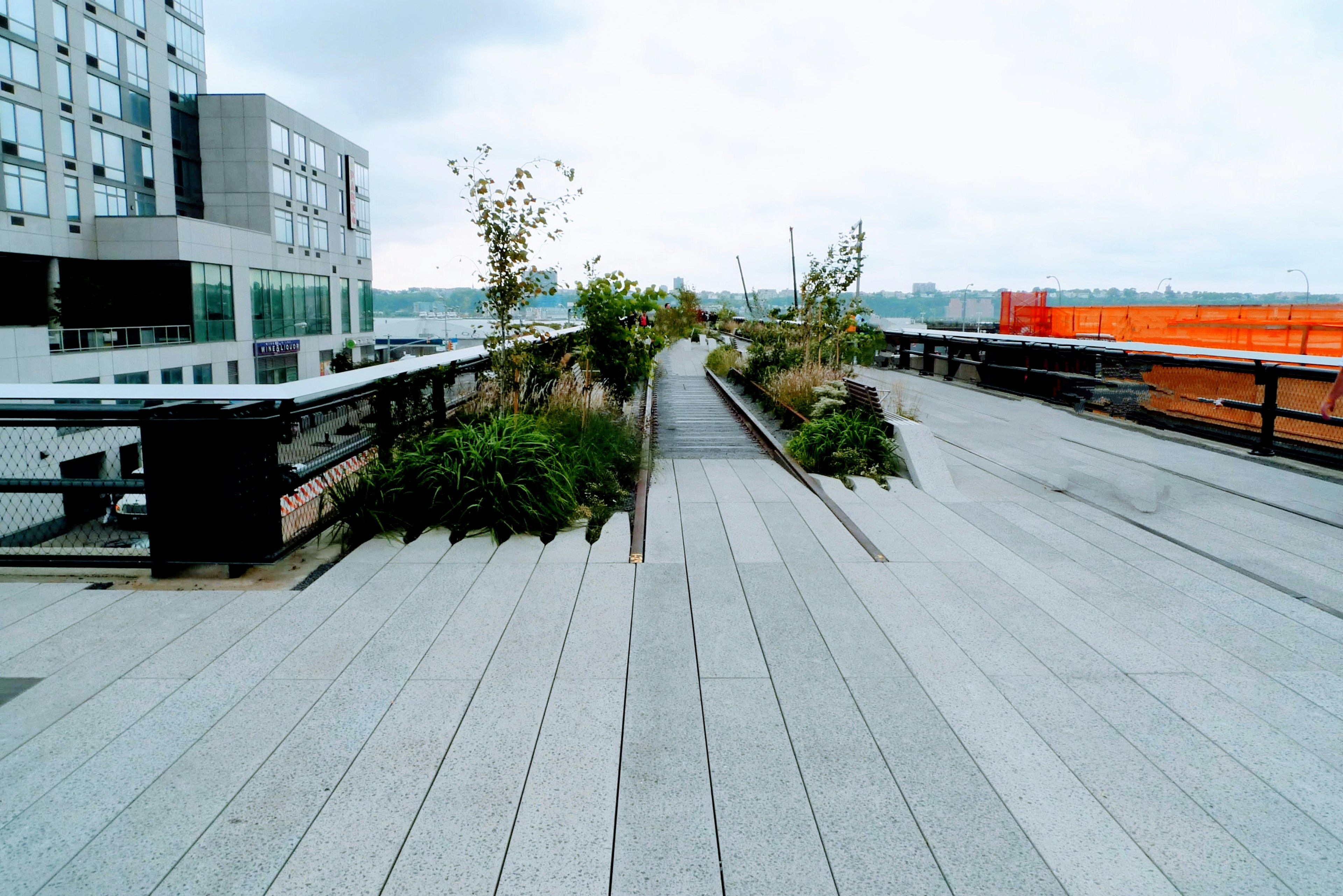 Elevated park pathway featuring greenery and modern buildings