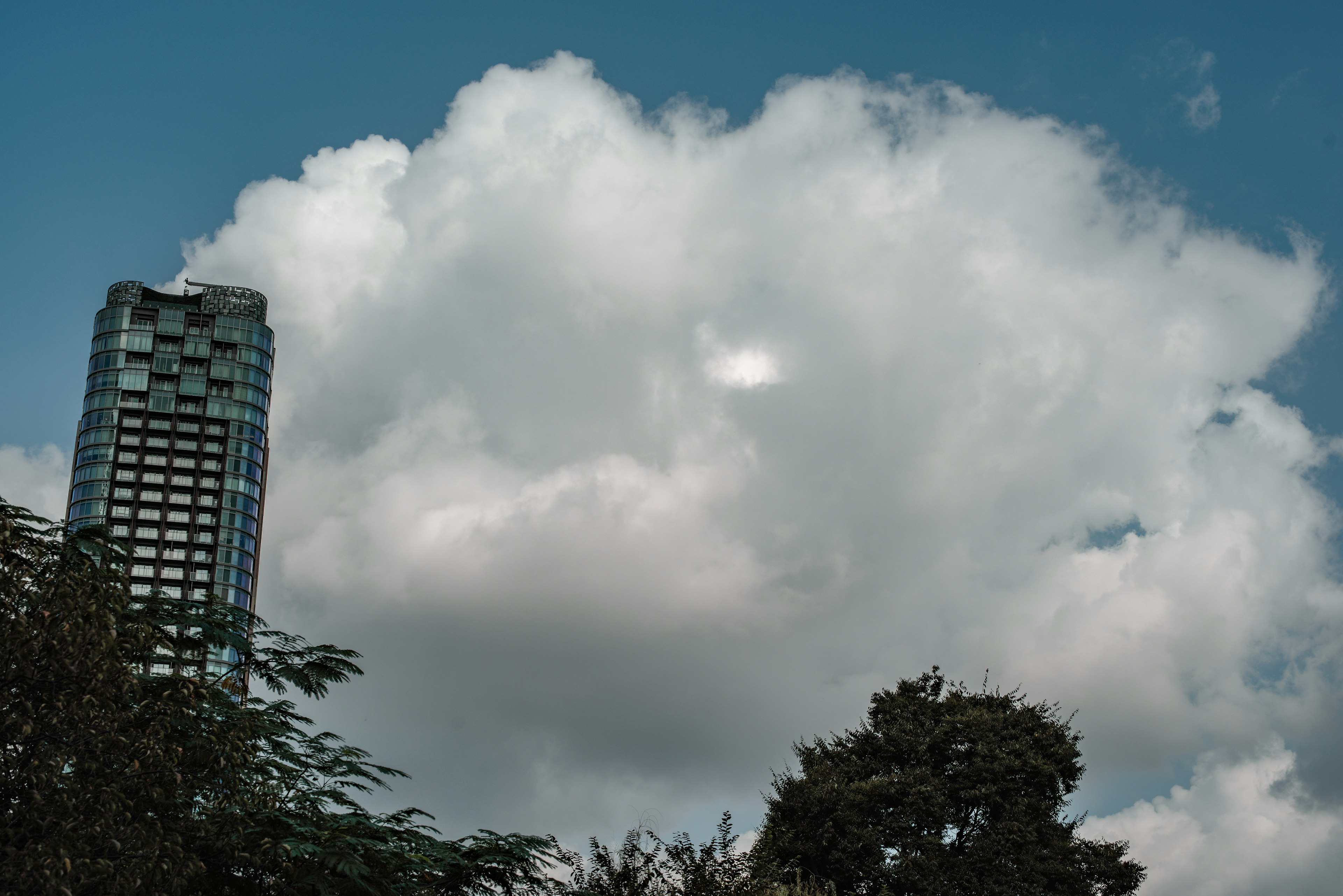 Große Wolke schwebt unter einem blauen Himmel mit einem Teil eines Wolkenkratzers