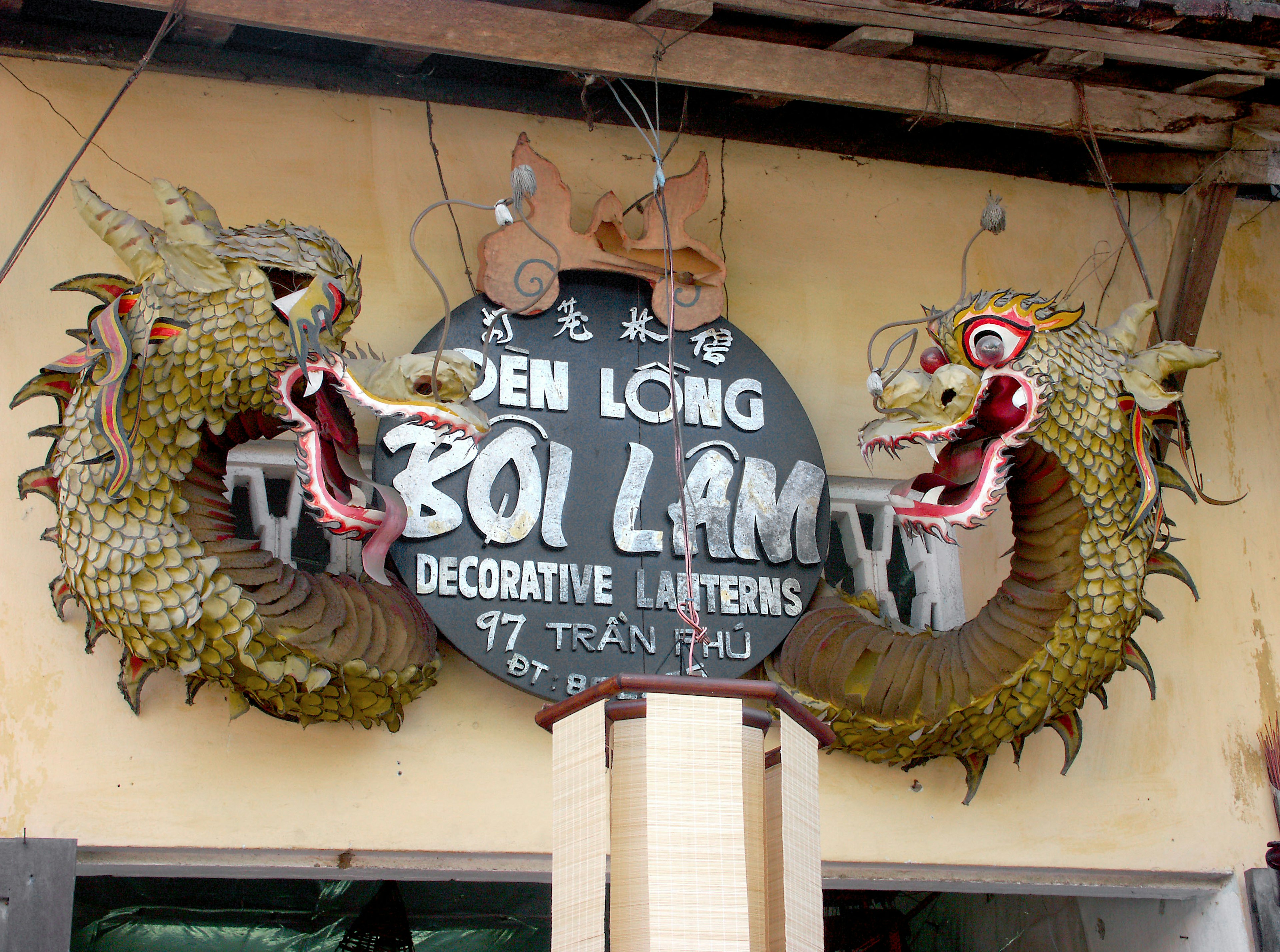 Sign featuring dragon sculptures with decorative lanterns