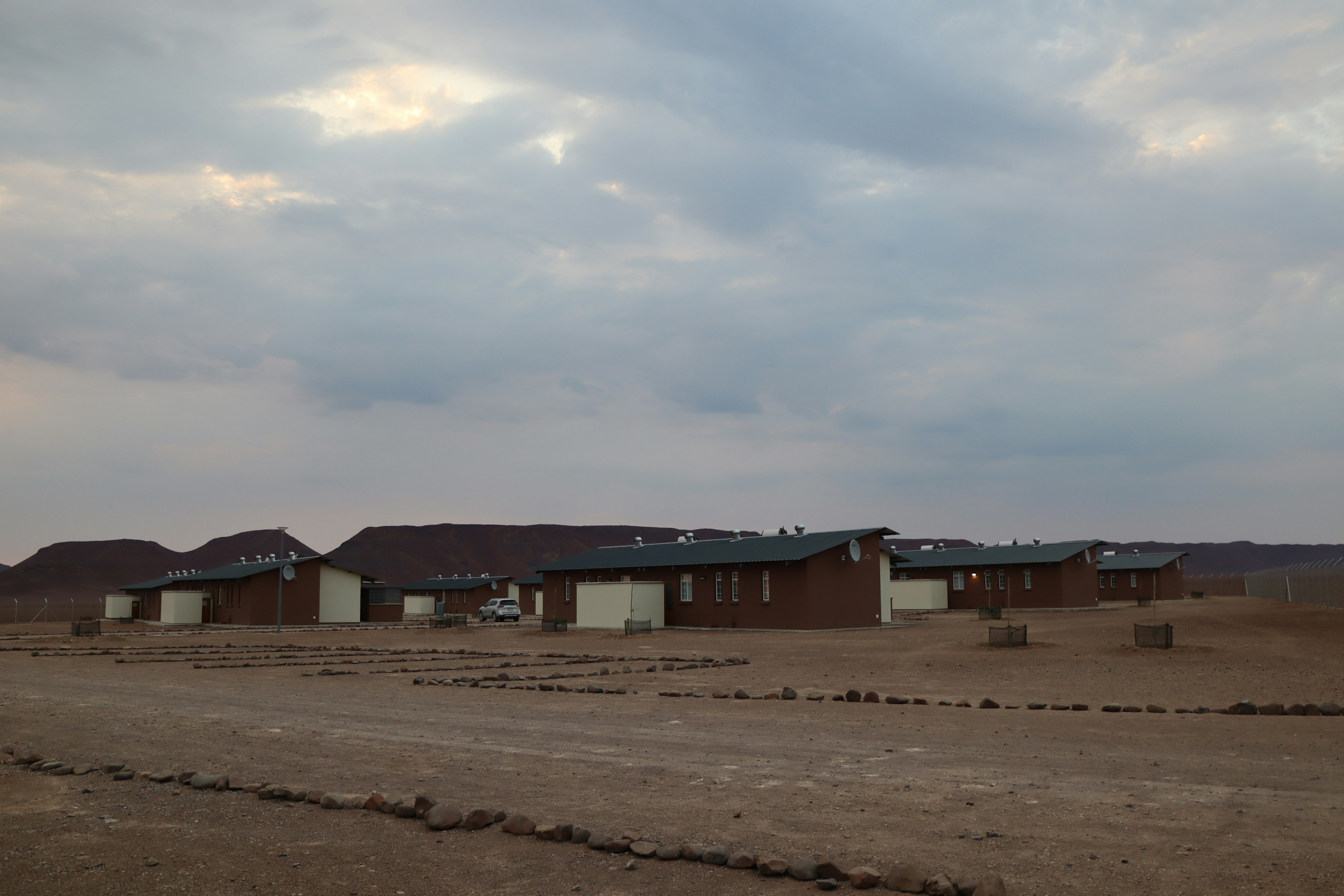 Pequeñas casas dispersas en un vasto desierto bajo un cielo nublado