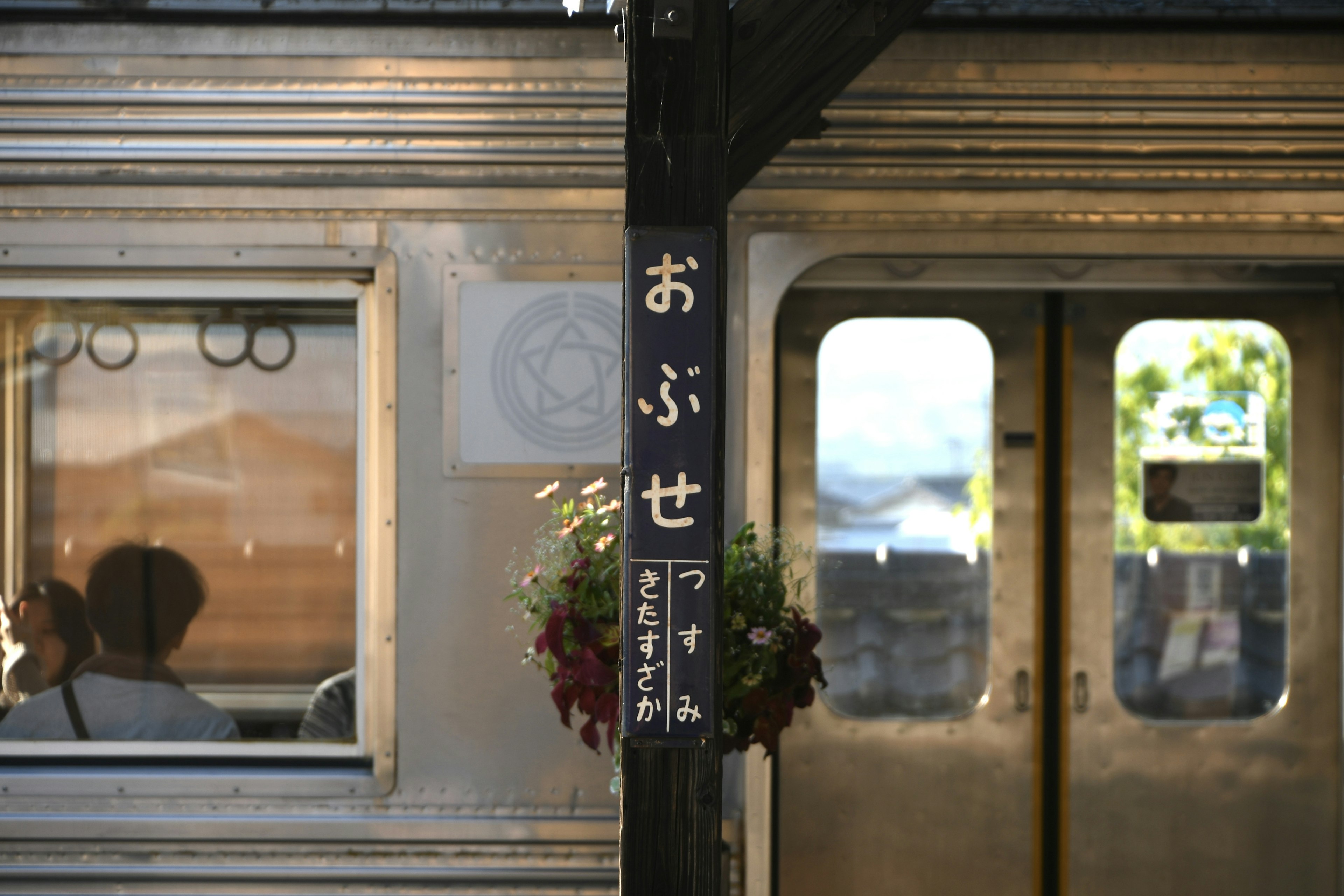 列車のドアと看板が映る風景 乗客が窓越しに見える