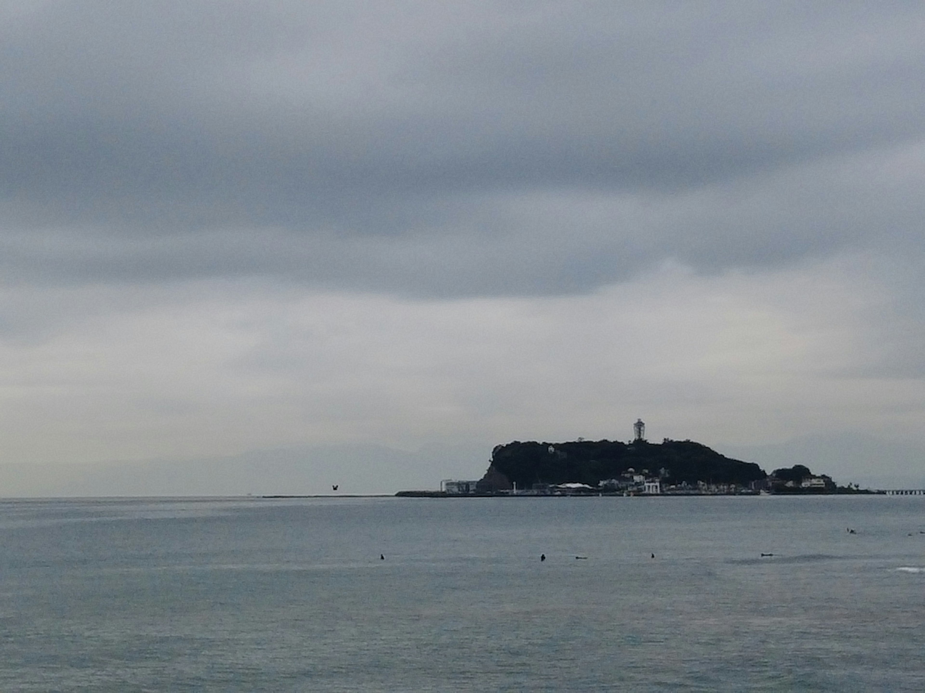 Scenic view of a small island with a lighthouse in the ocean