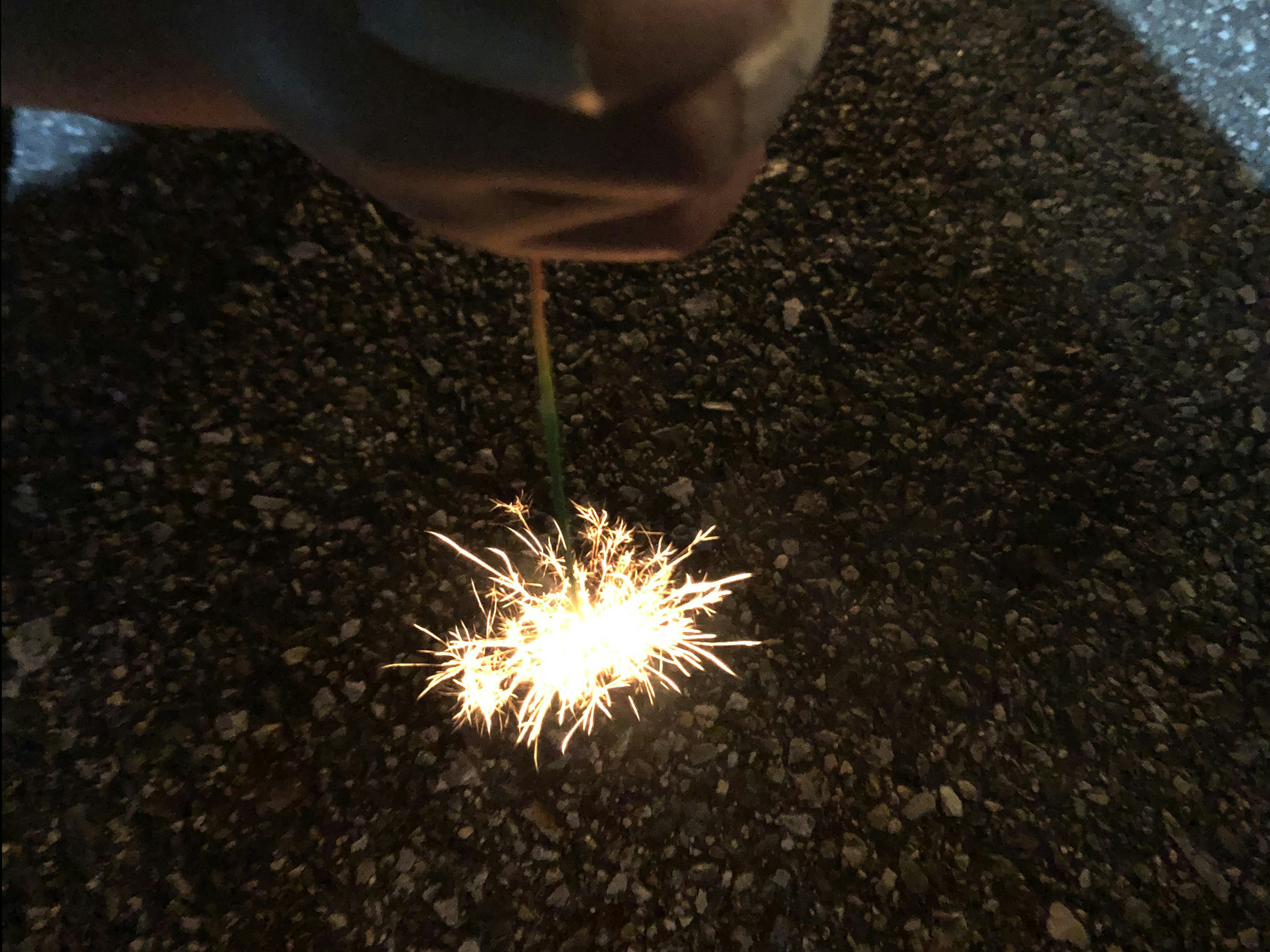 Un fuego artificial sostenido en la mano brillando sobre un fondo oscuro