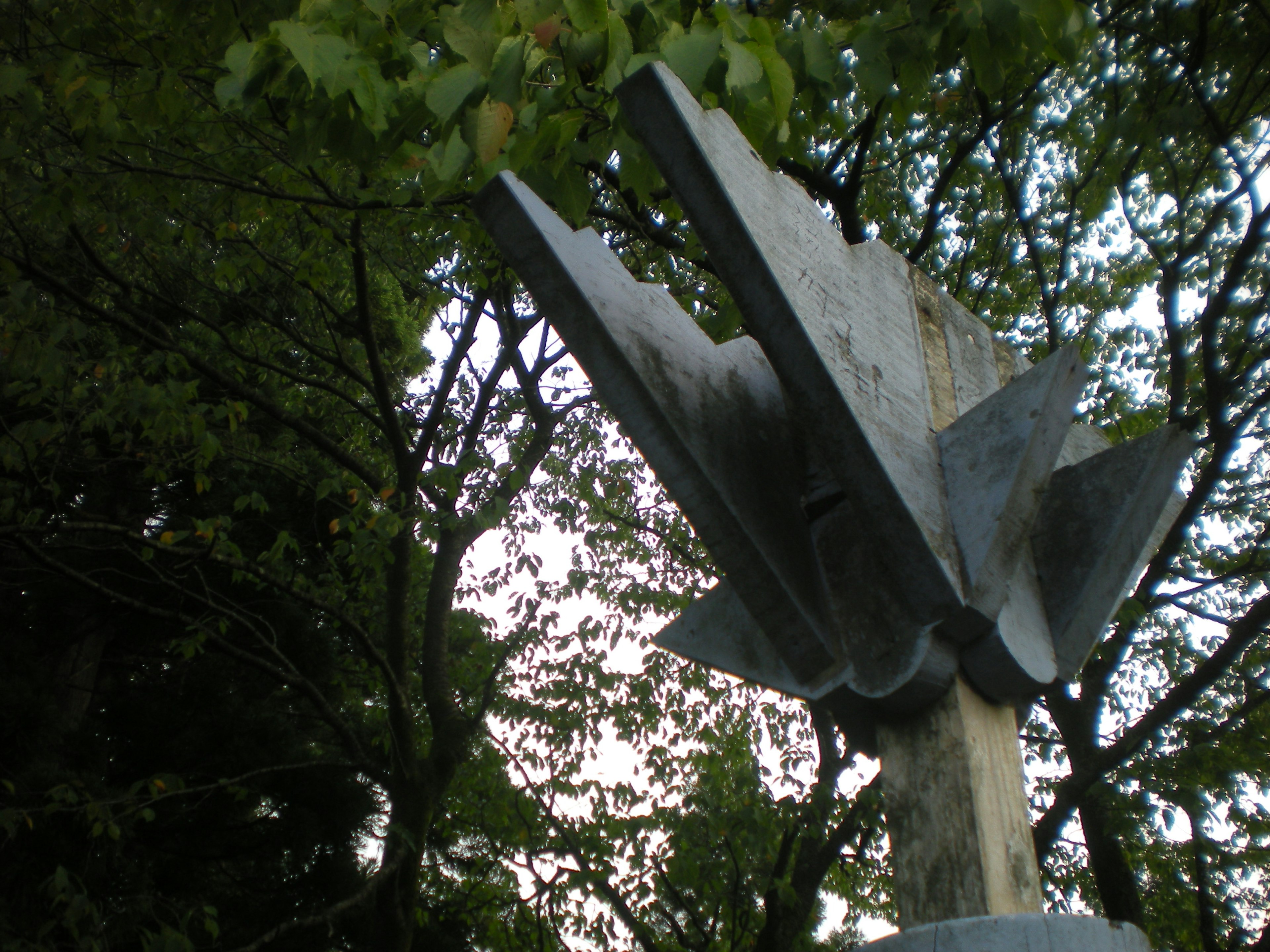 Escultura de metal con bordes afilados rodeada de árboles