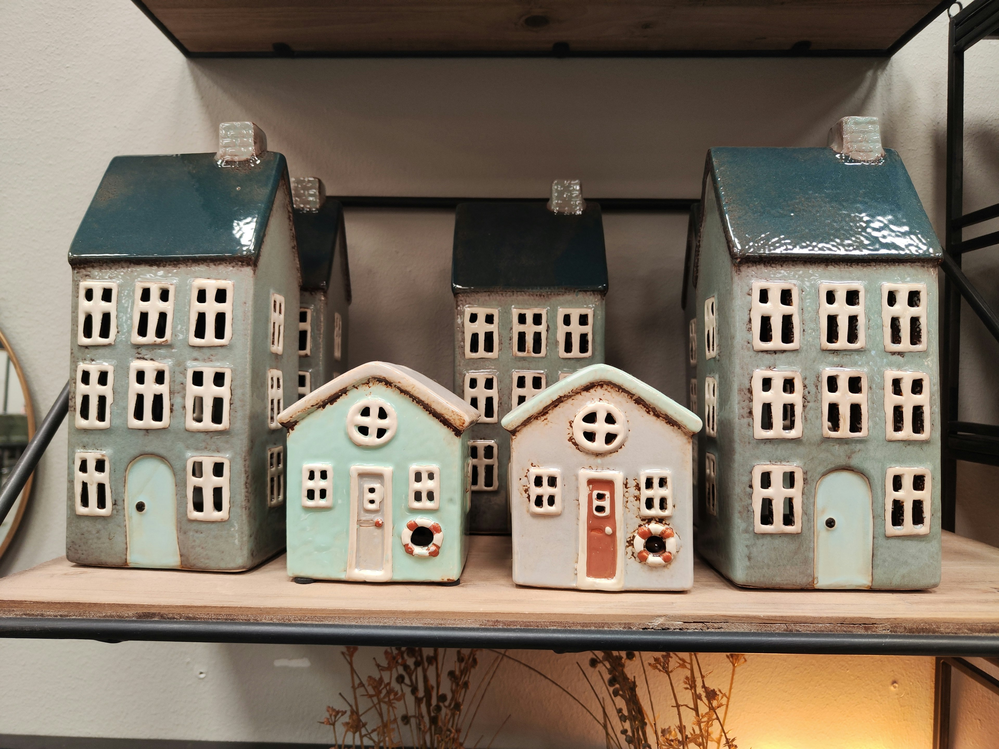 A collection of ceramic houses with blue roofs displayed on a shelf