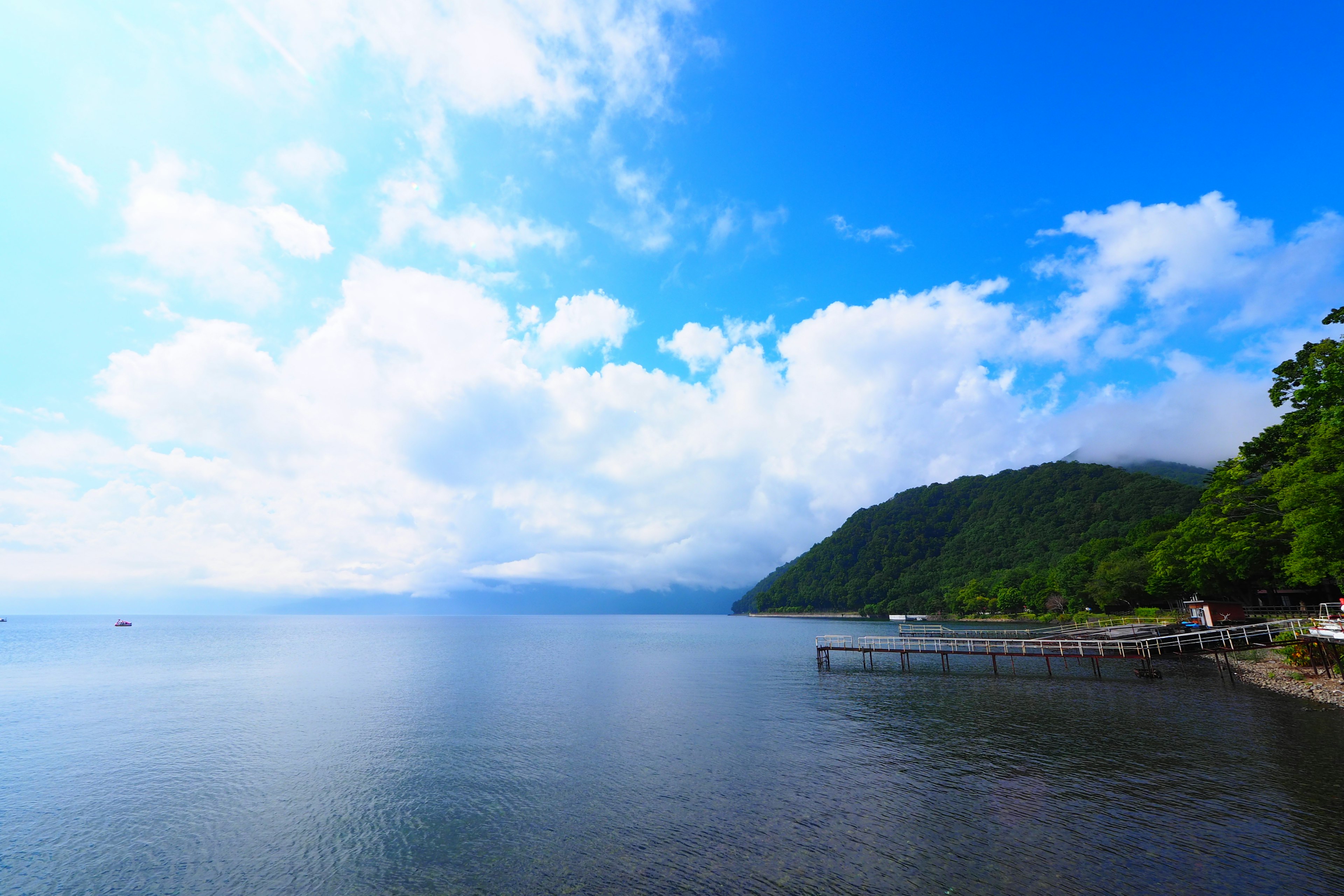 Lac calme avec ciel bleu et nuages blancs collines vertes en arrière-plan