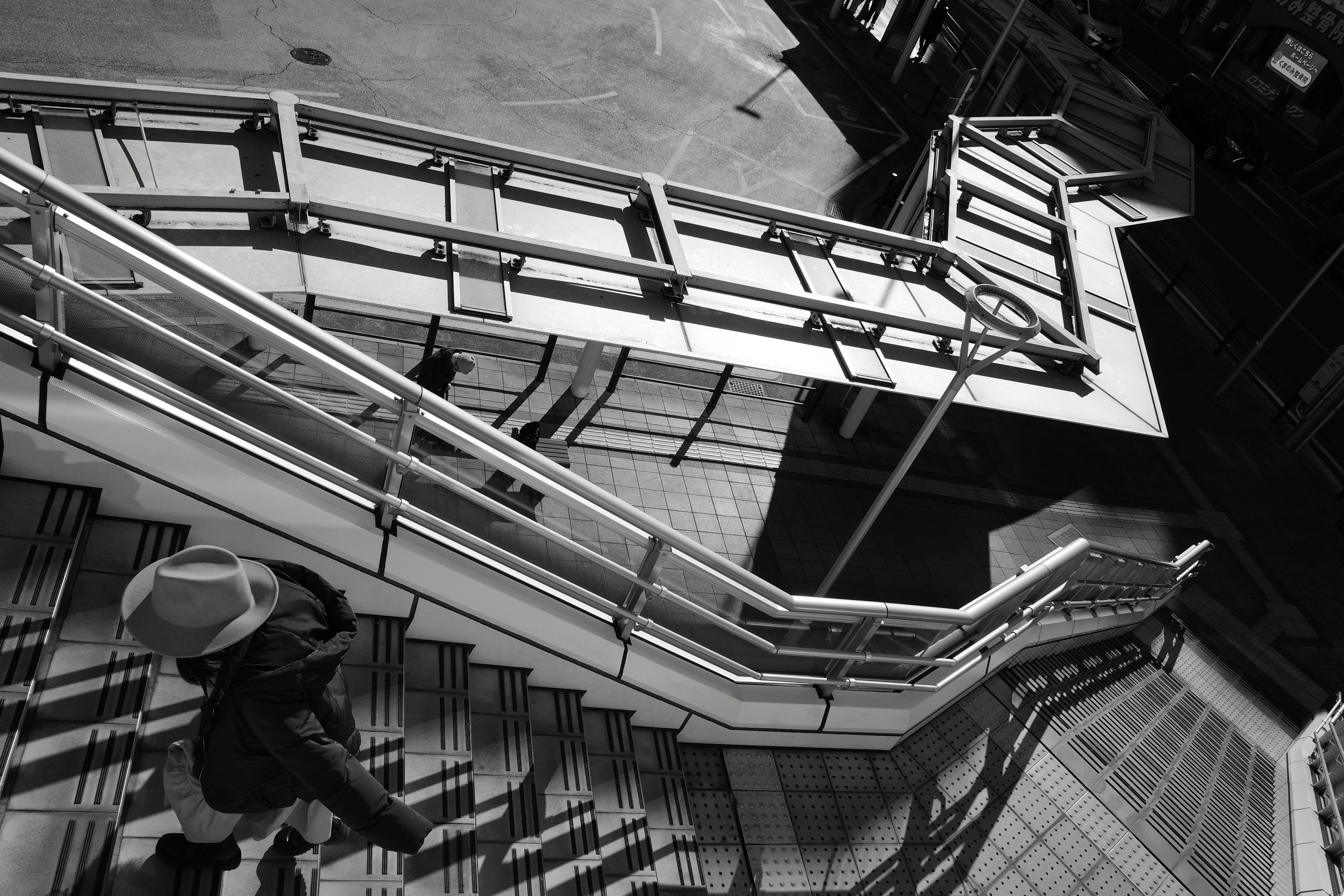 Black and white image of a person ascending a staircase with railings