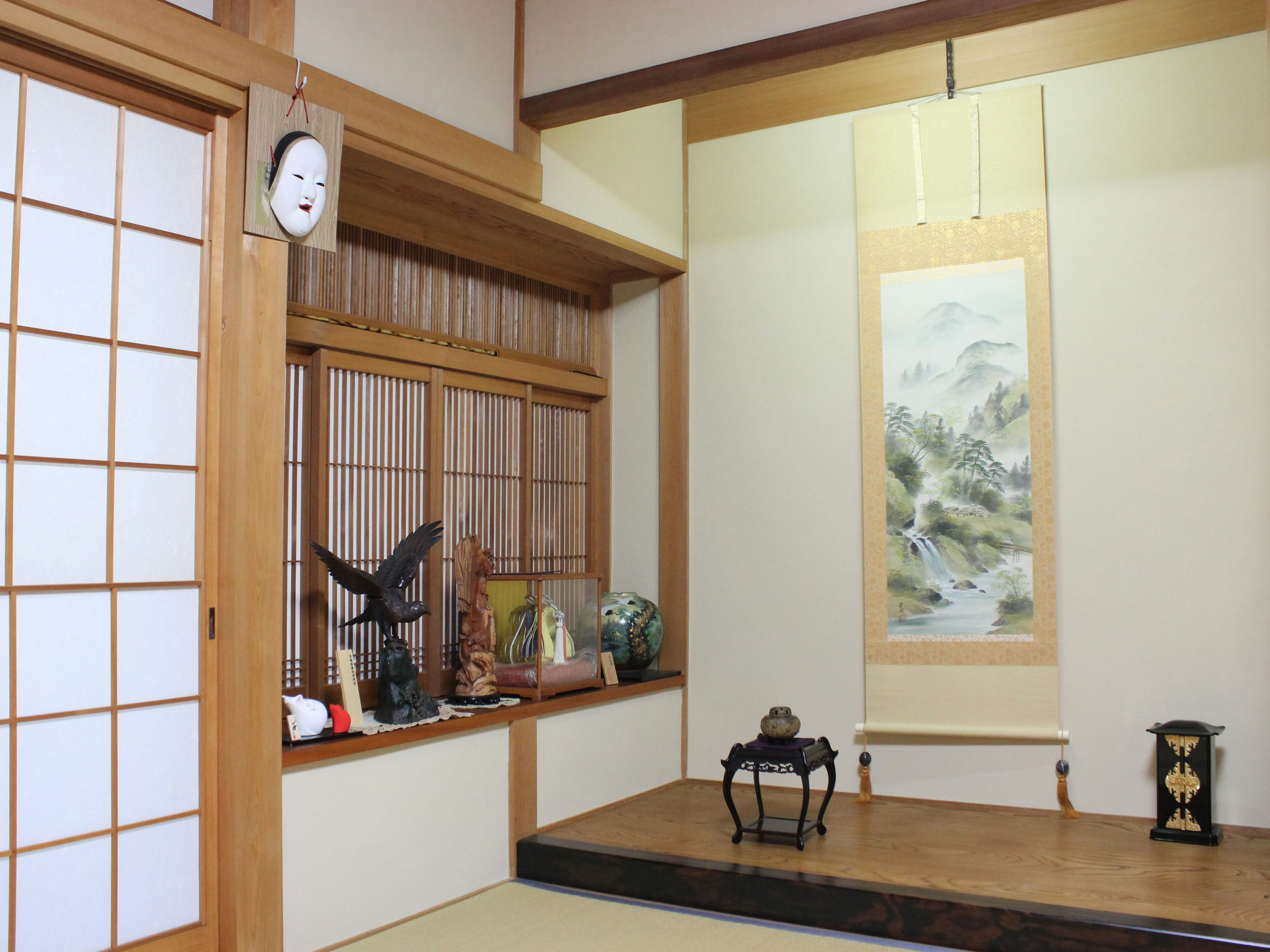 Traditionelles japanisches Zimmerinterieur mit Holzrahmen und Shoji-Bildschirmen, die Rollen und Dekorationsgegenstände zeigen