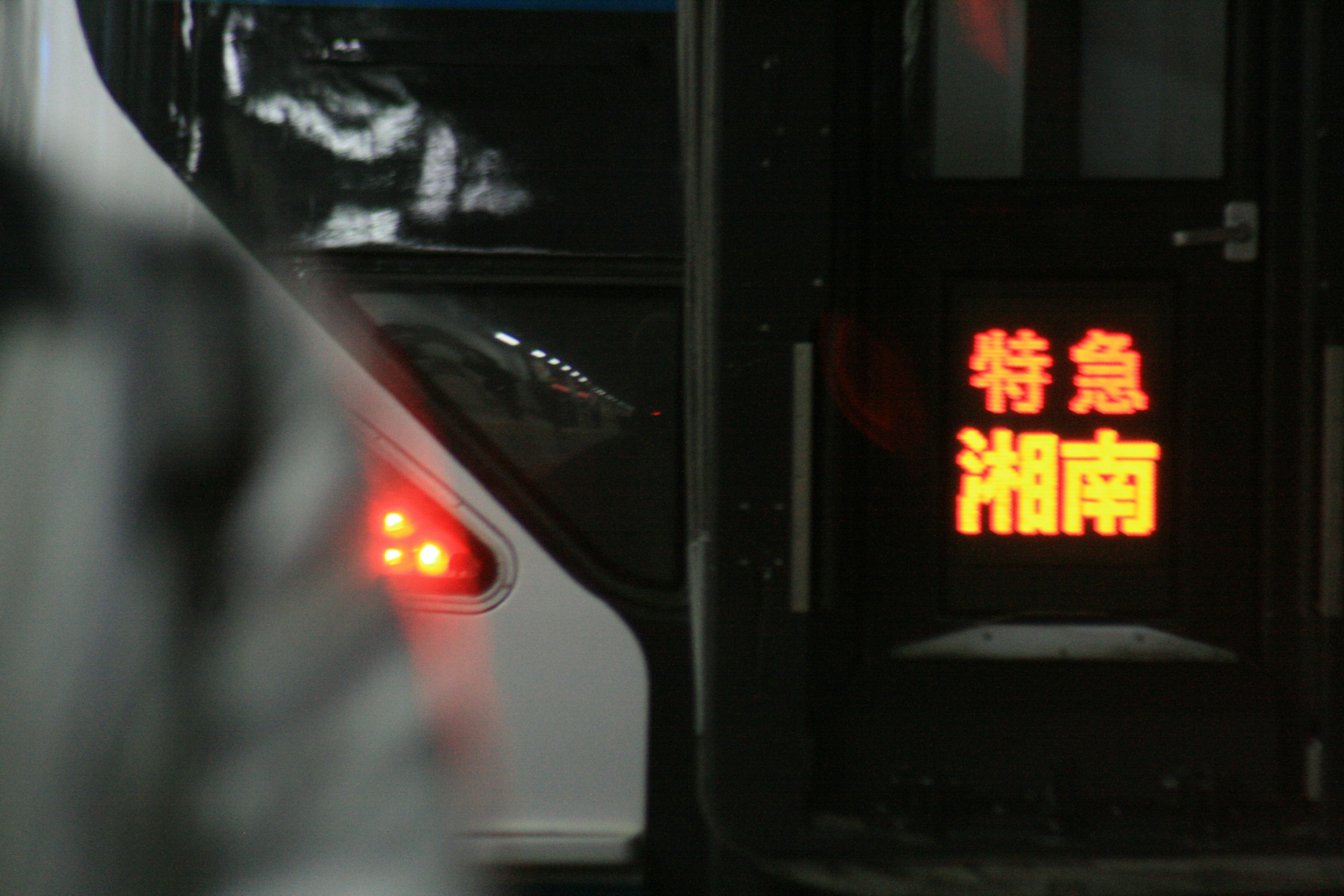 Eine Person in der Nähe der Tür eines Busses mit dem Express Shonan-Schild