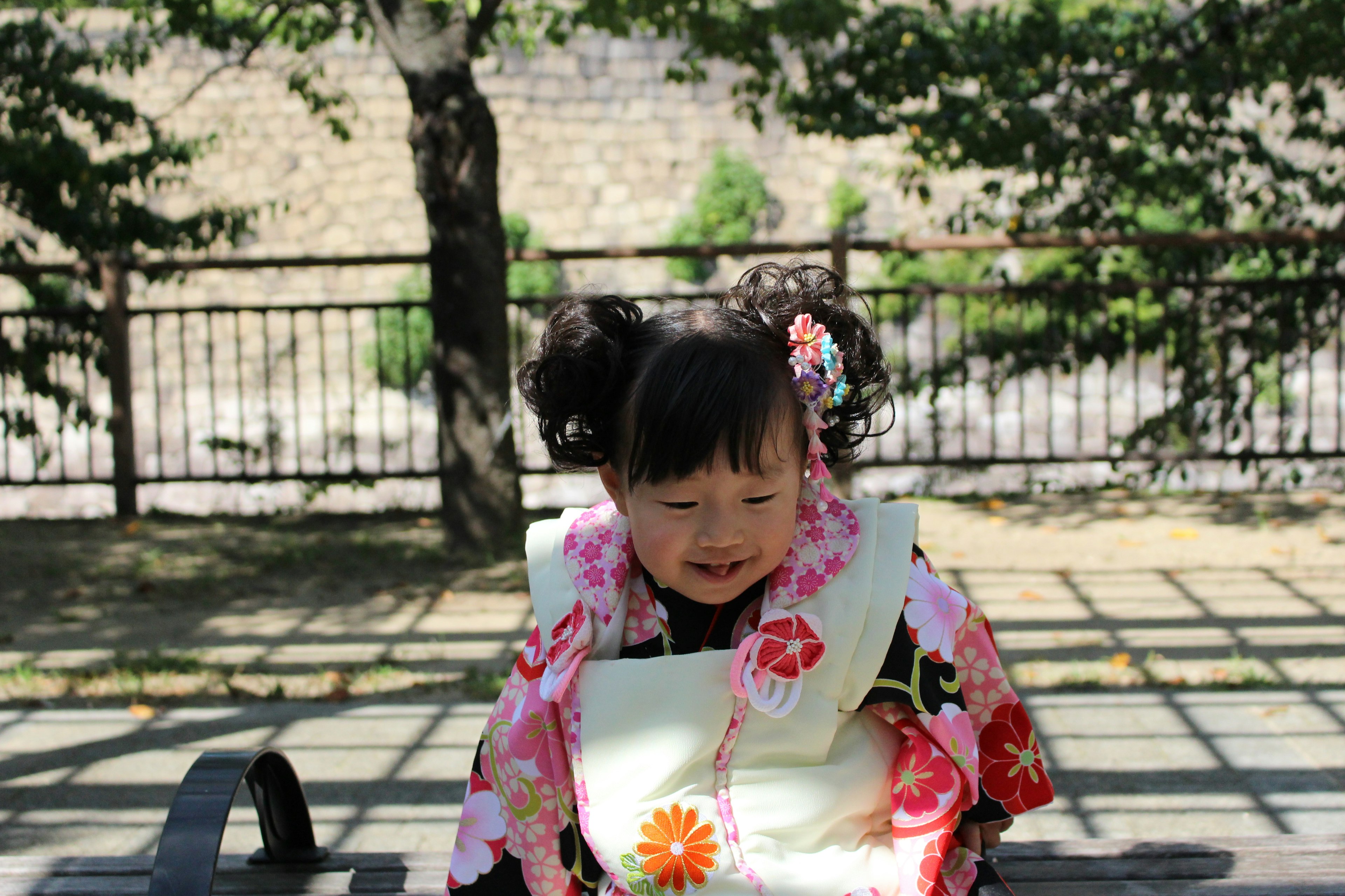 Niña pequeña con kimono sonriendo en un jardín