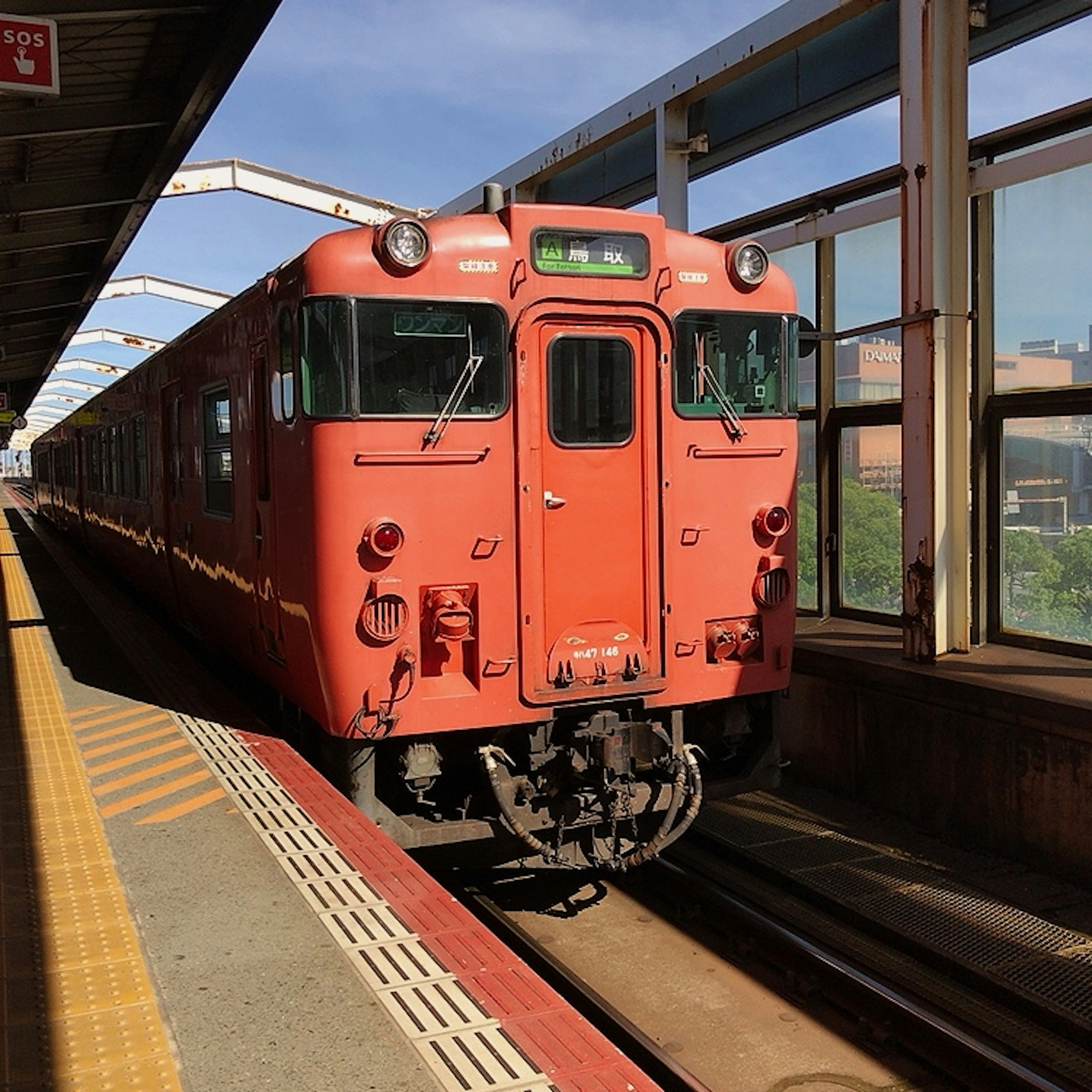 Kereta merah berhenti di stasiun dengan langit biru