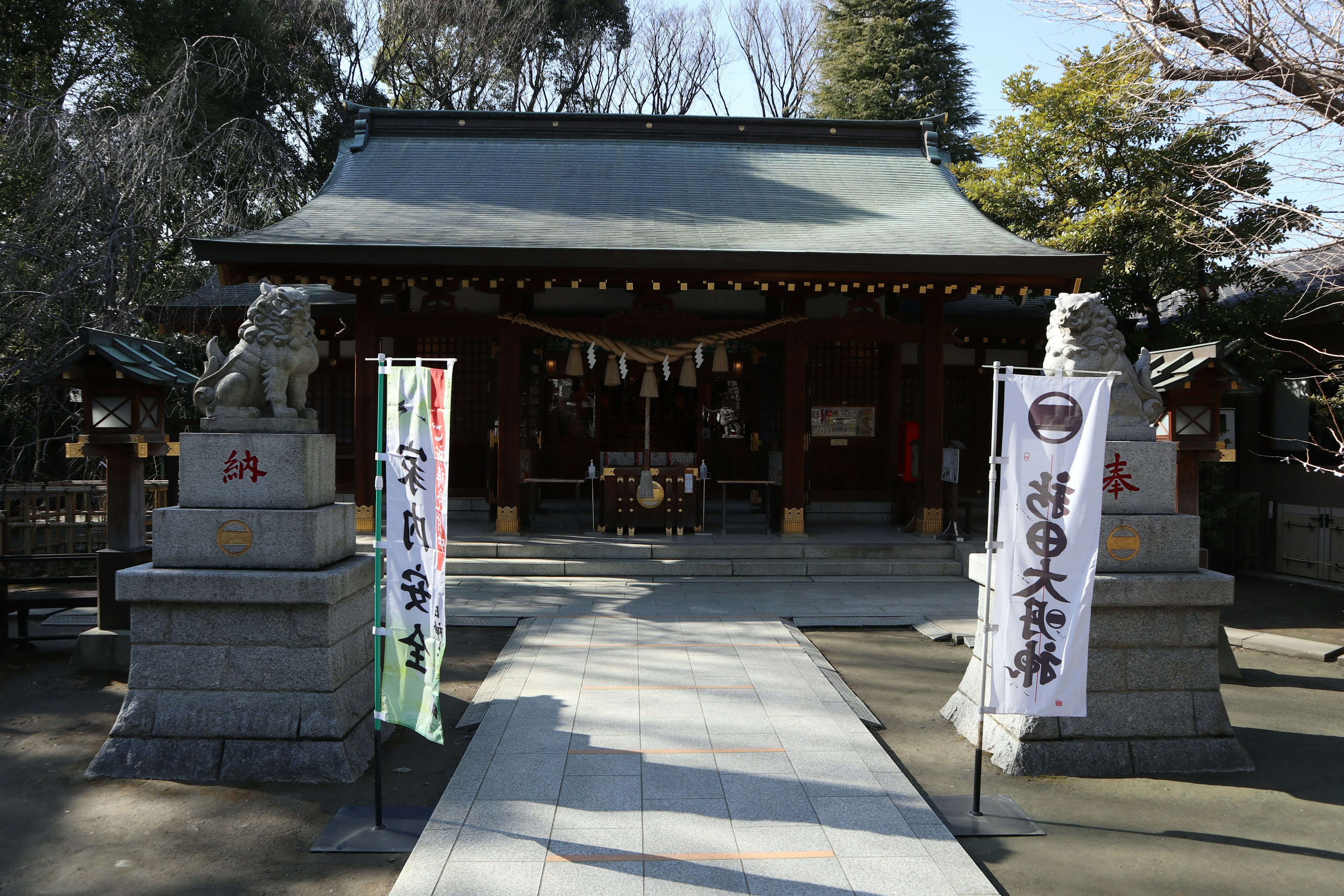 神社の入り口にある狛犬とのれんが特徴的な風景