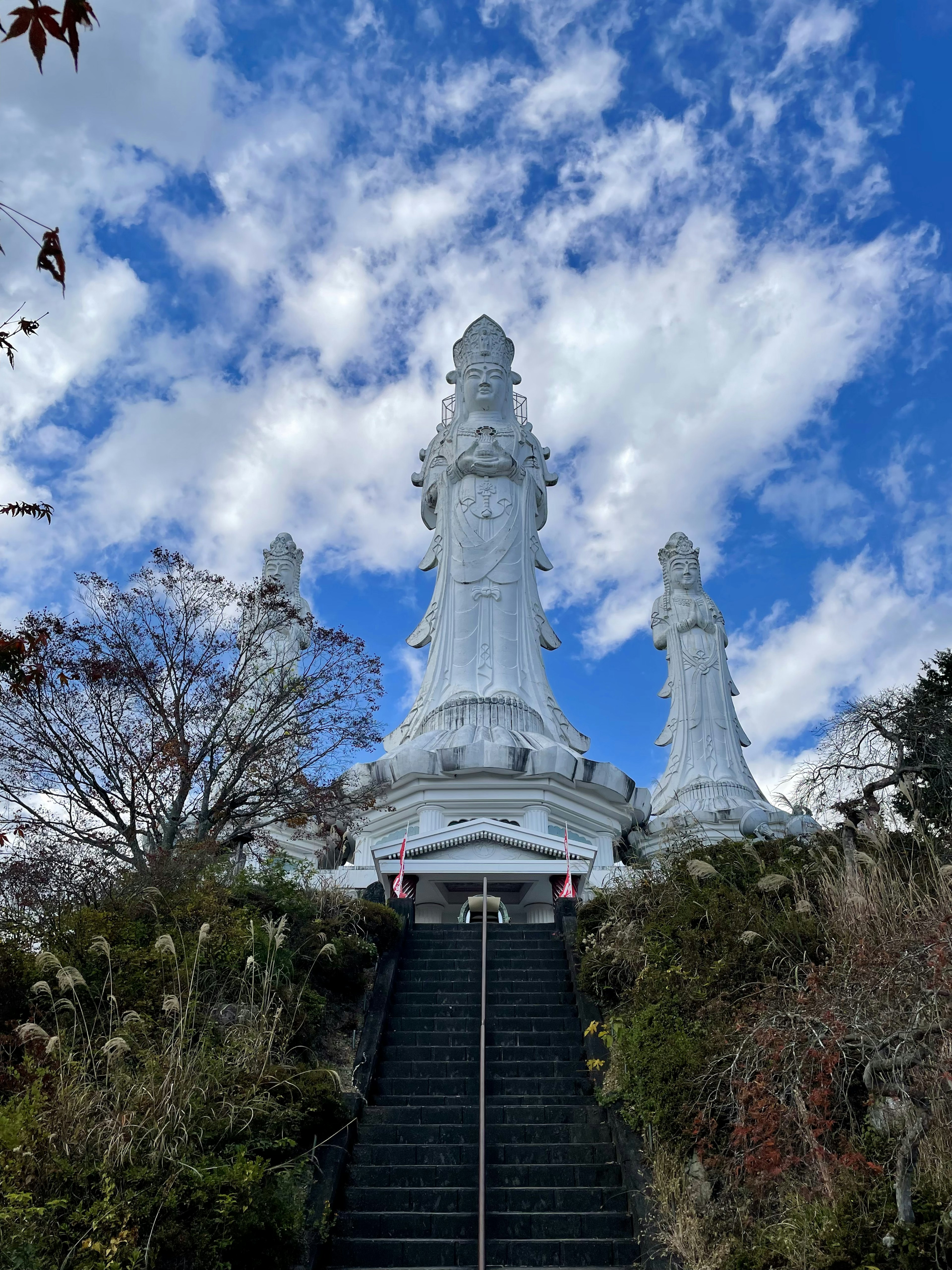 Estatuas blancas con escaleras bajo un cielo azul con nubes