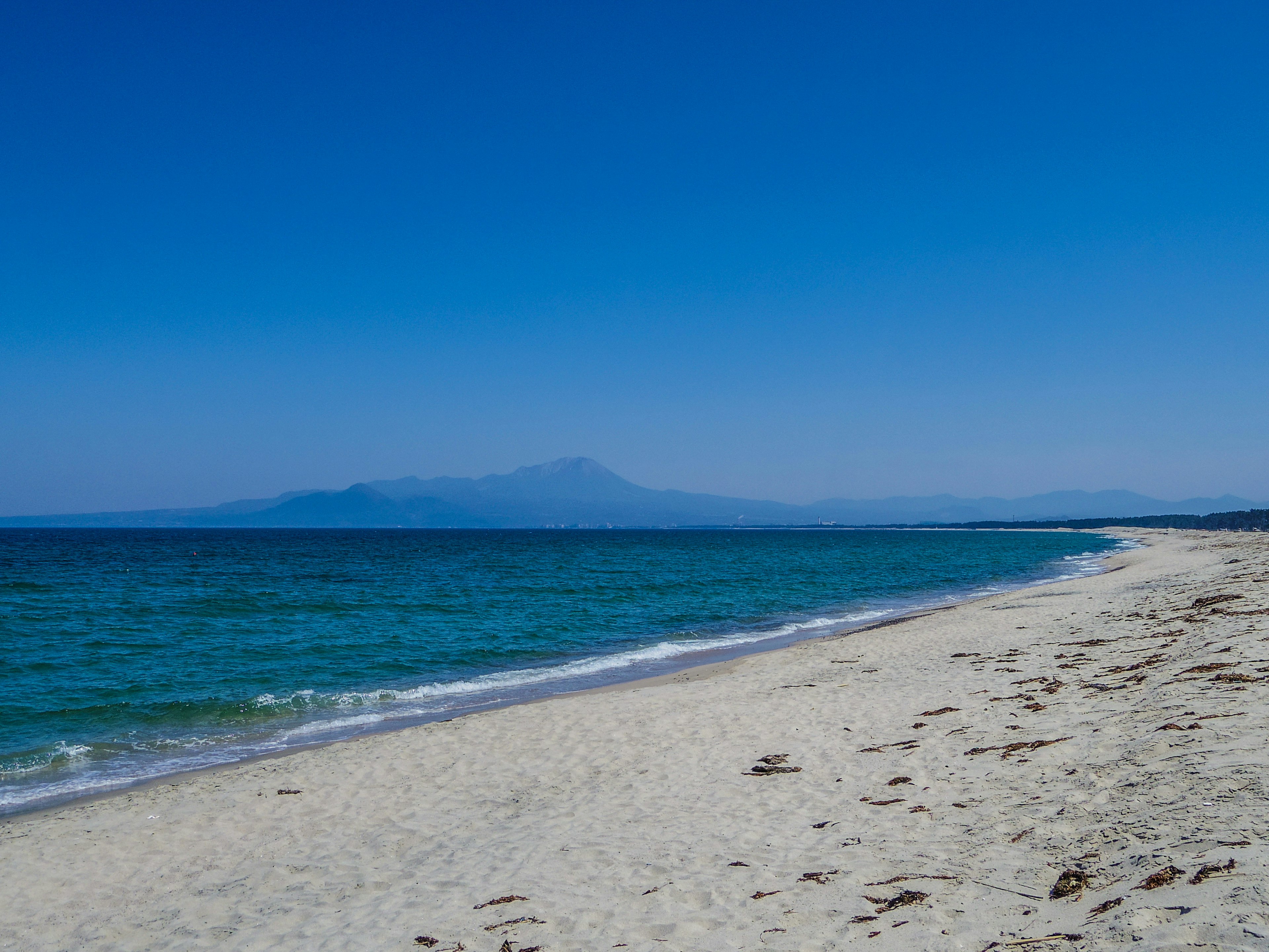 Une vue pittoresque de la mer bleue et de la plage de sable blanc avec des montagnes au loin