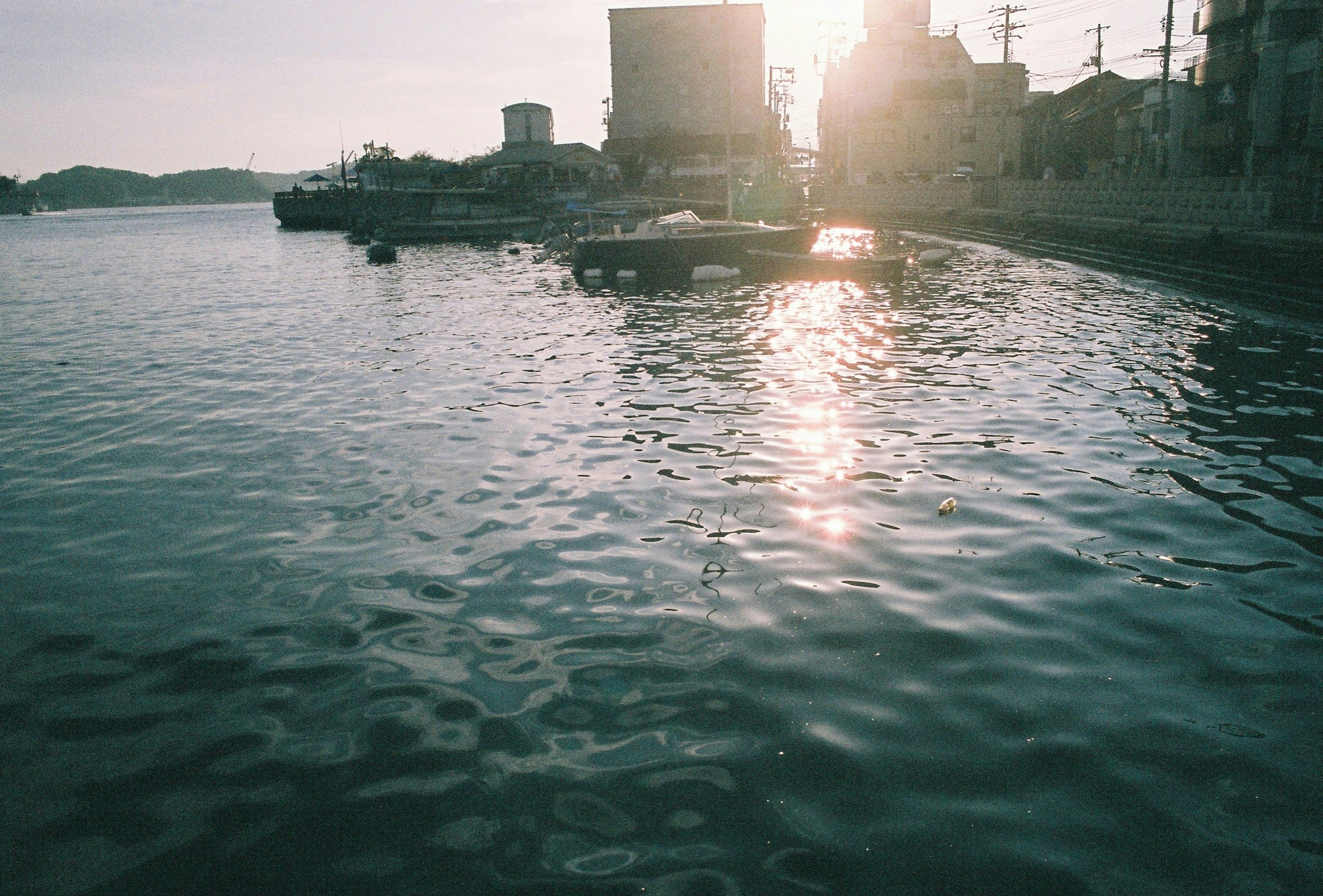 Water surface reflecting sunlight with a serene waterfront