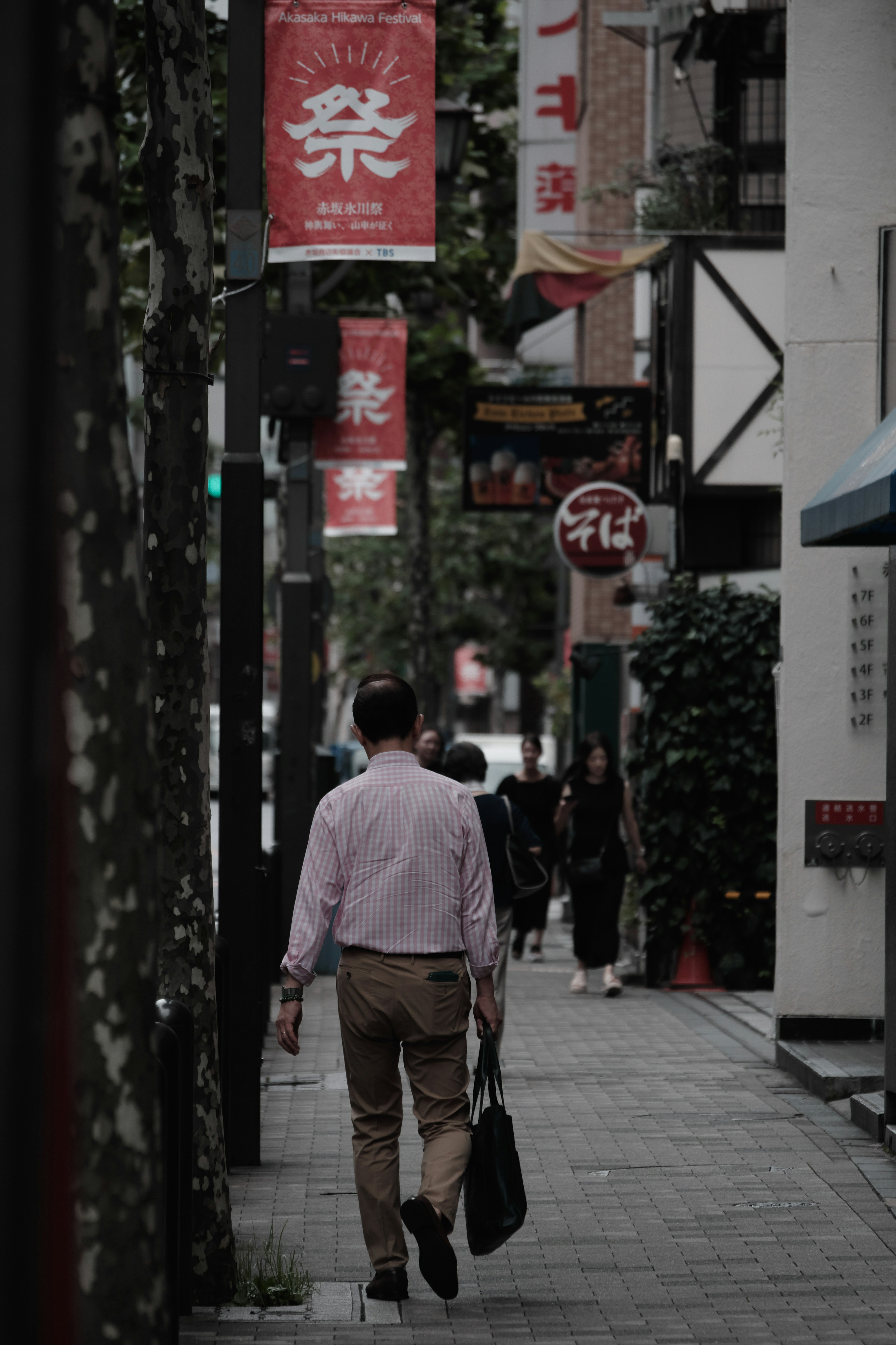 Un hombre caminando por una calle con pancartas rojas