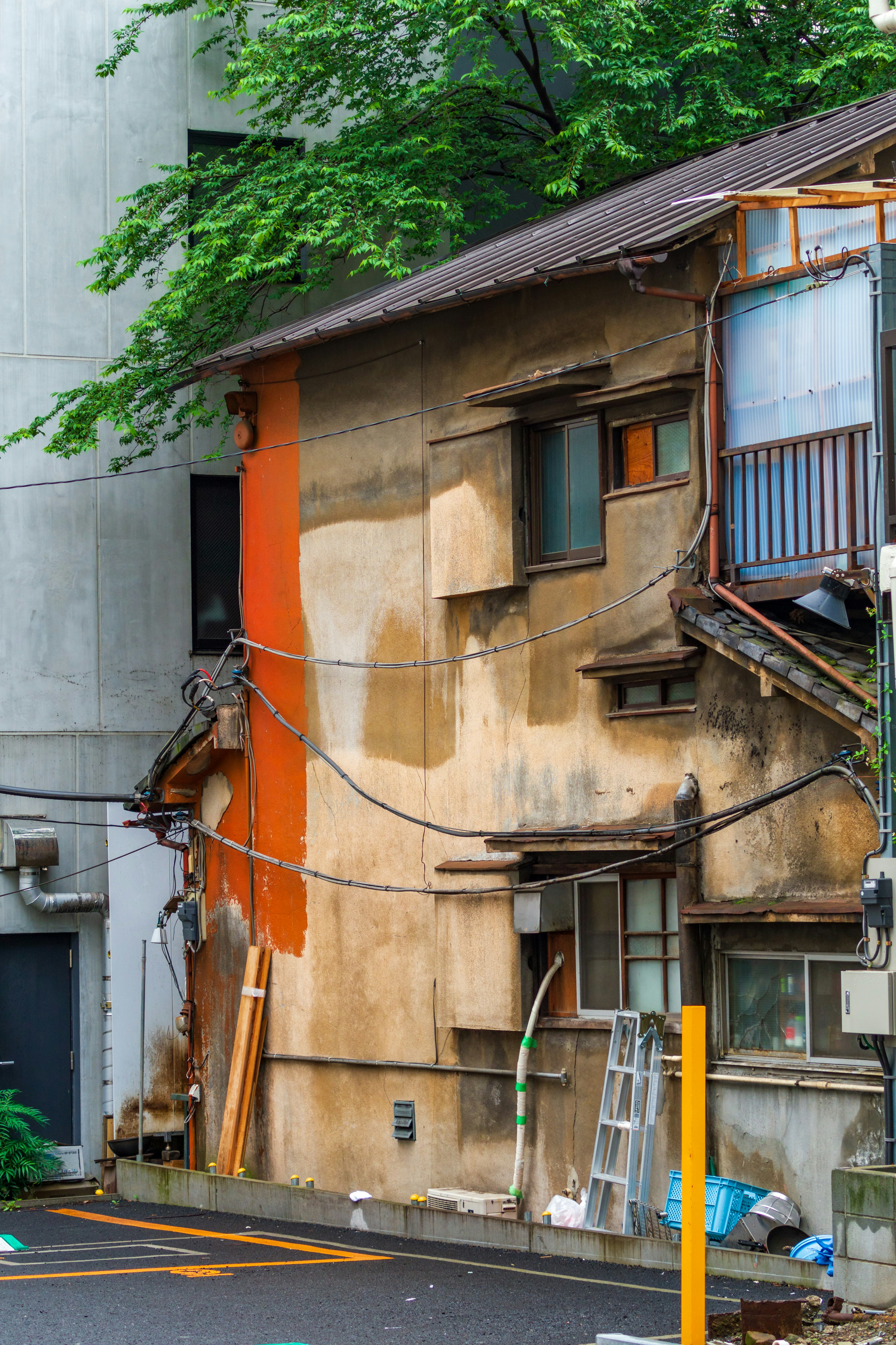 A weathered building with an orange section contrasting with surrounding greenery