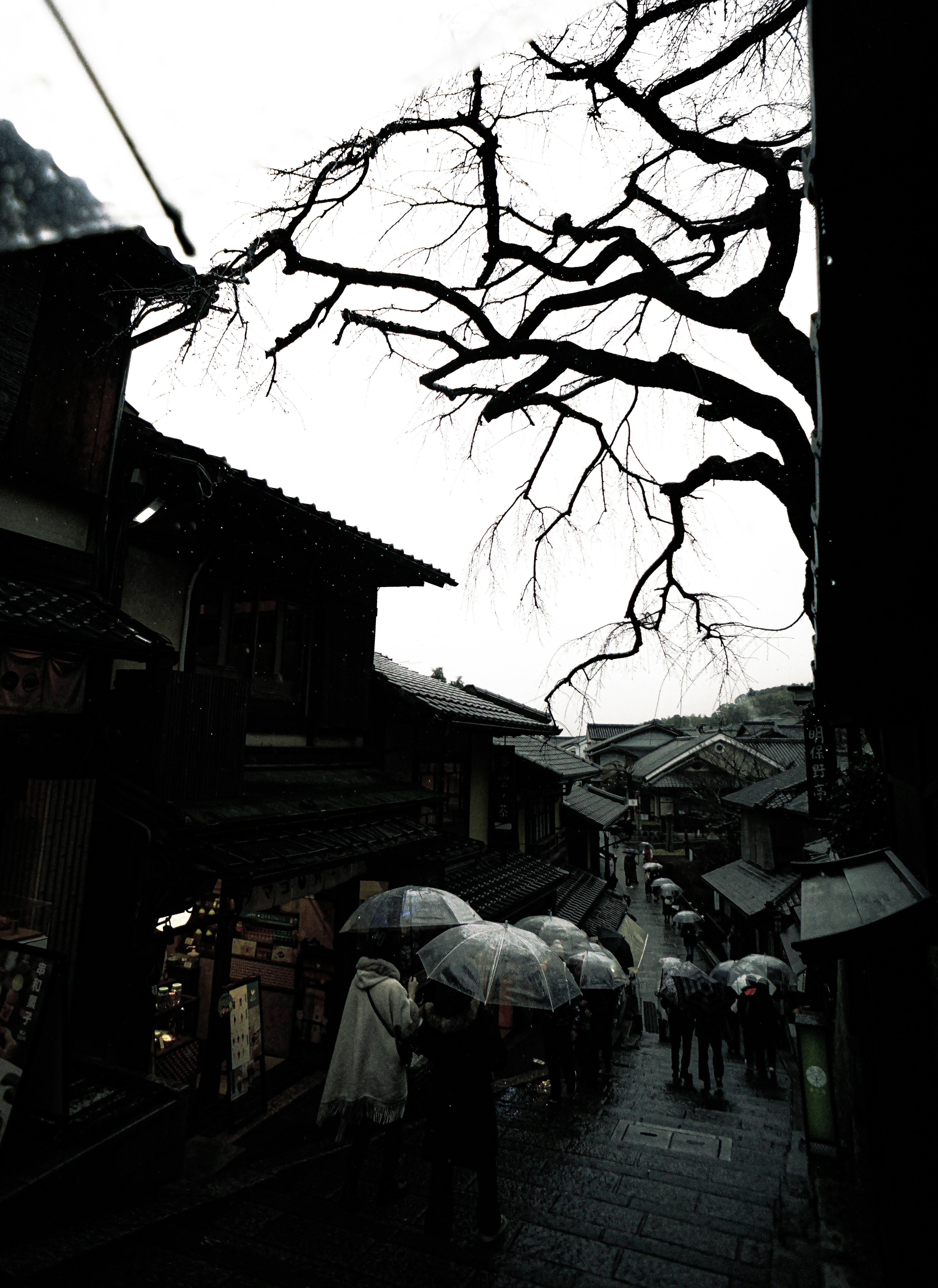 Historic street scene with people holding umbrellas in the rain