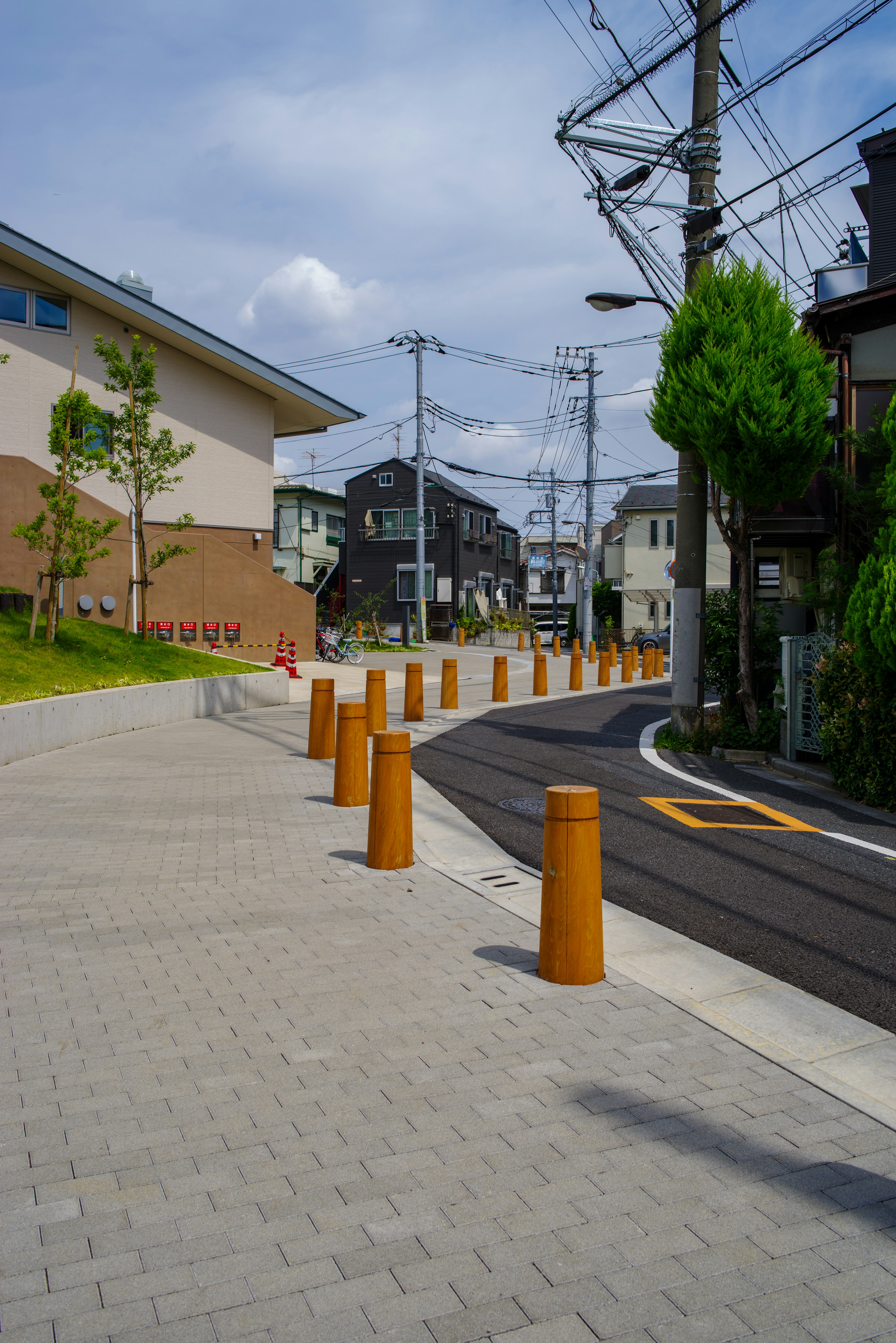 住宅街の舗装された歩道とオレンジ色のポールが並ぶ風景