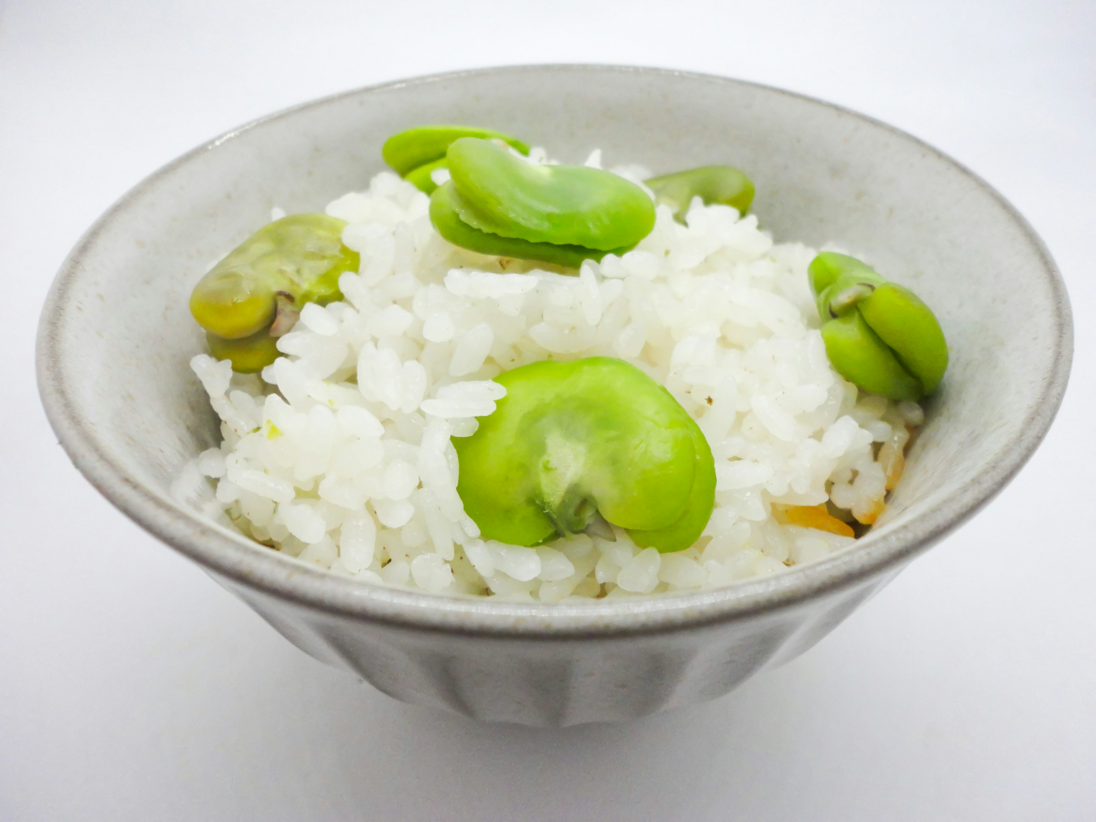 A bowl of white rice topped with green fava beans