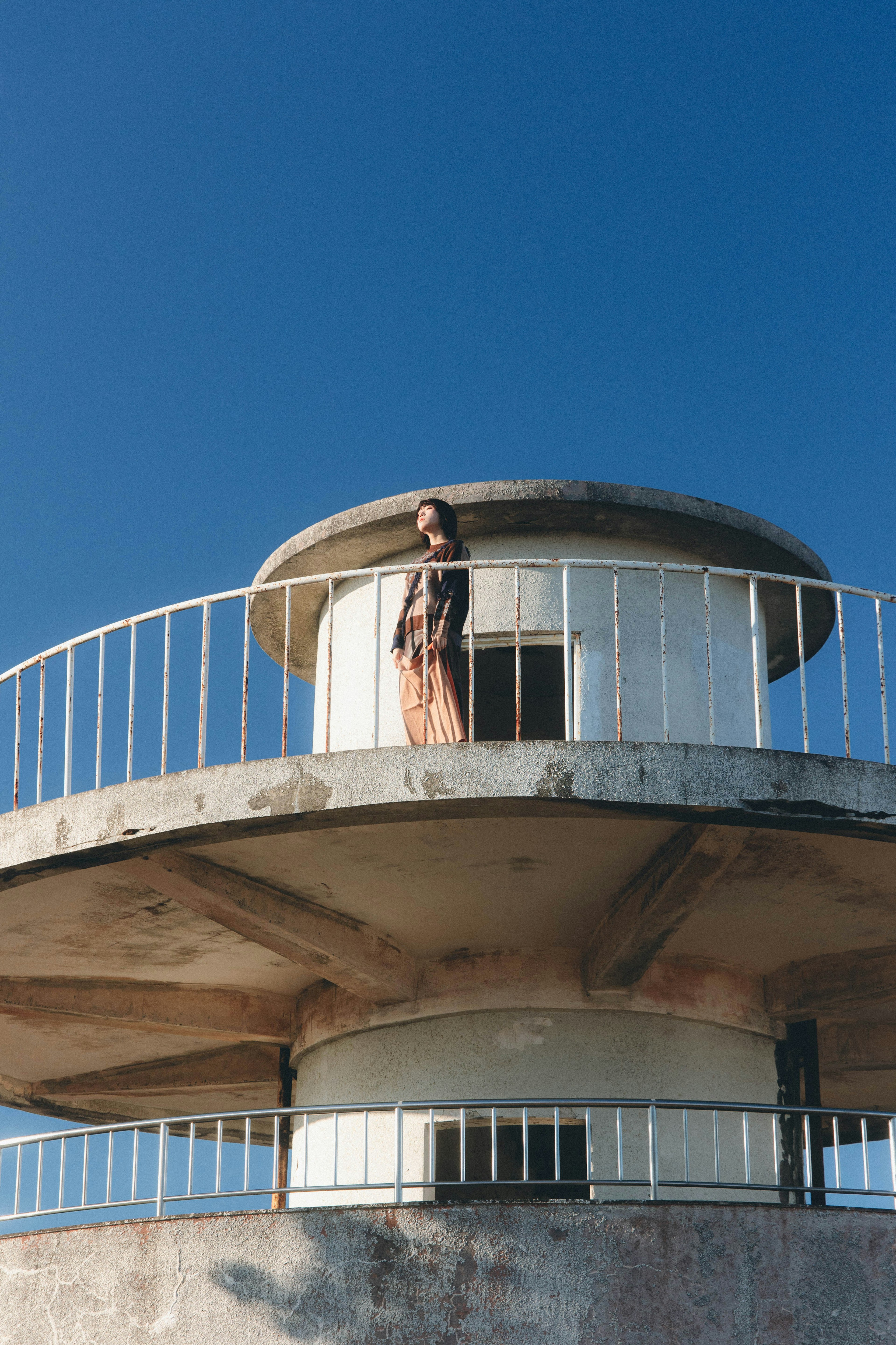 Una mujer de pie en la cima de un faro bajo un cielo azul