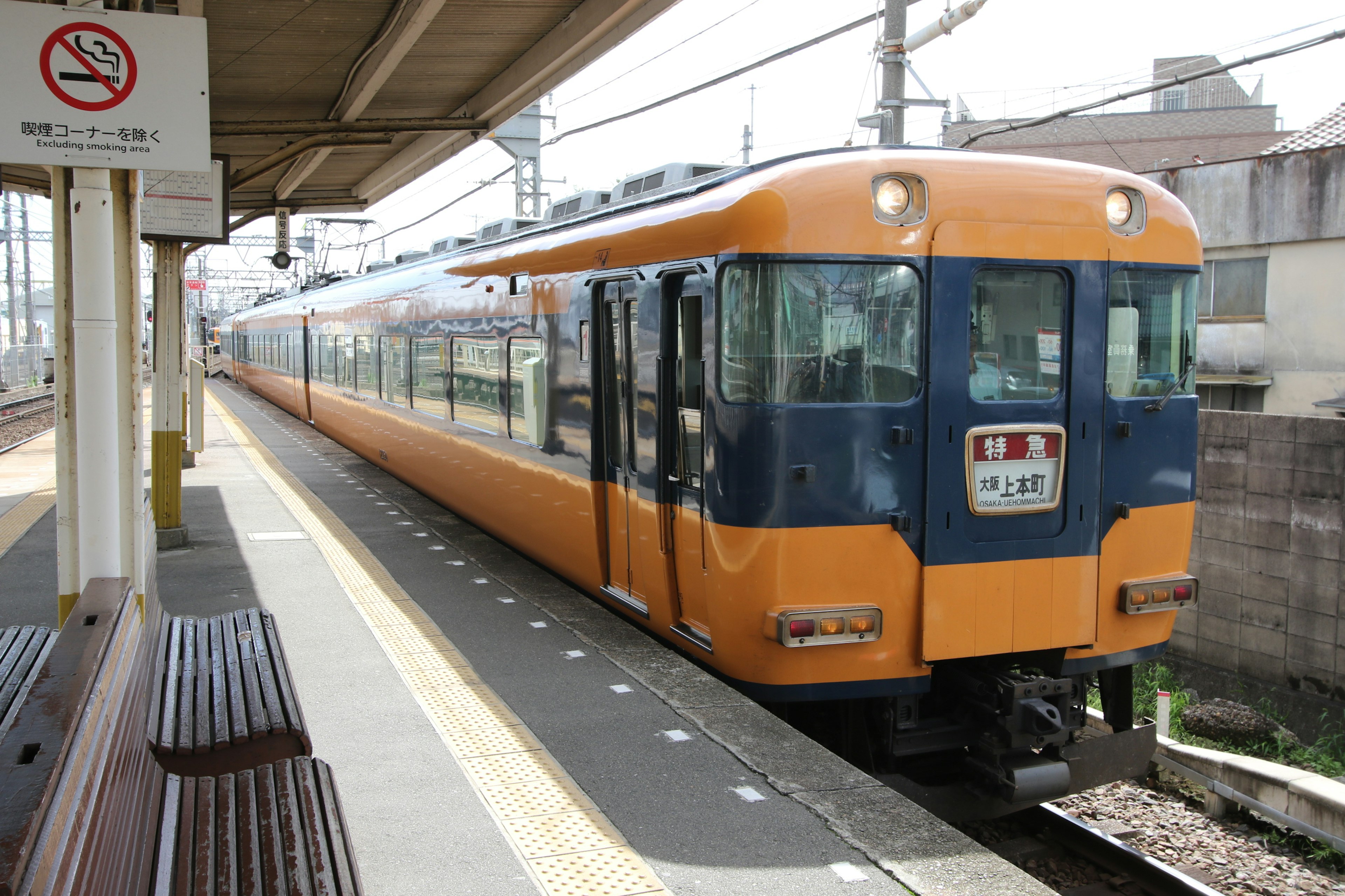 An orange train is stopped at a station platform