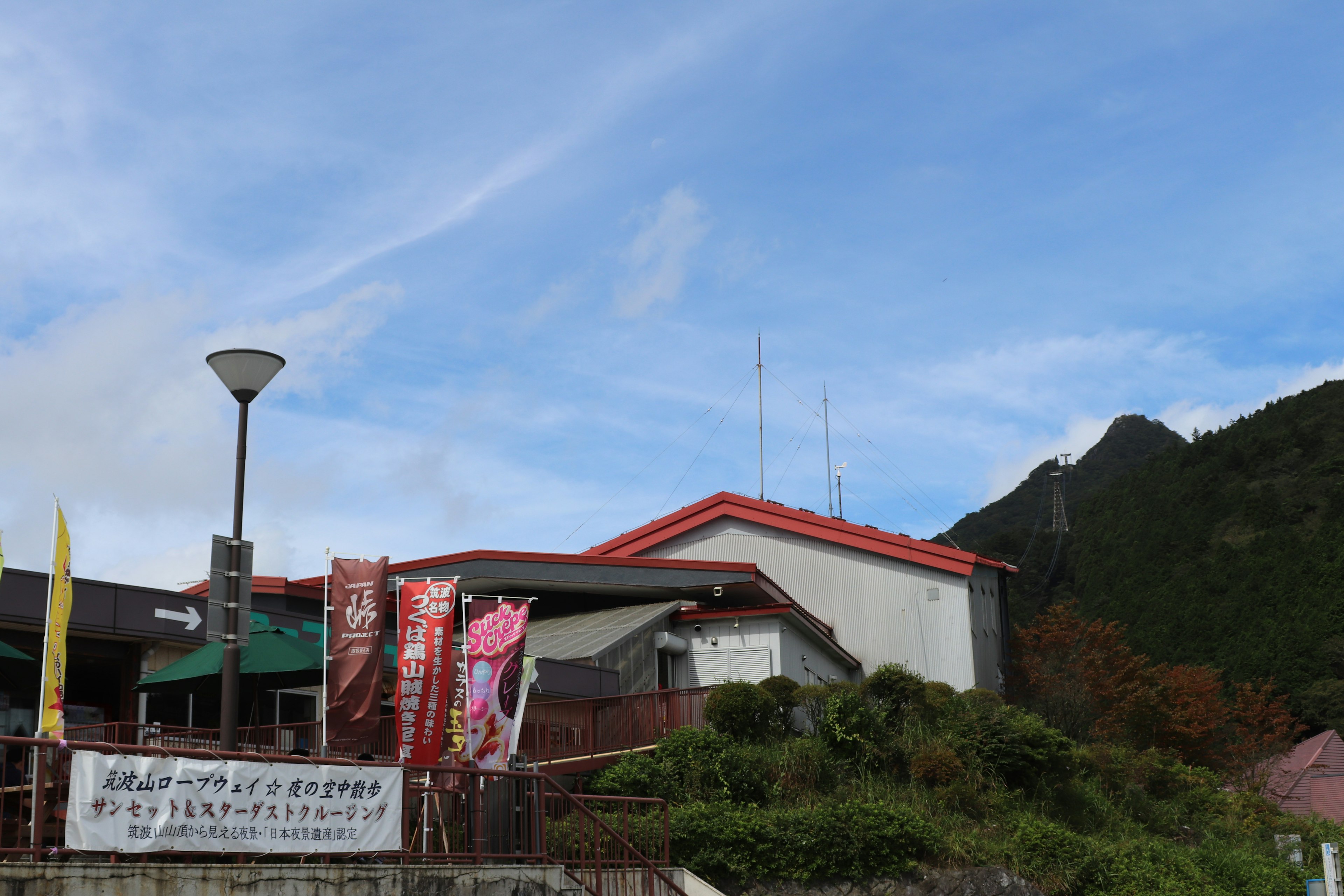 青空の下にある赤い屋根の建物と周囲の緑の風景