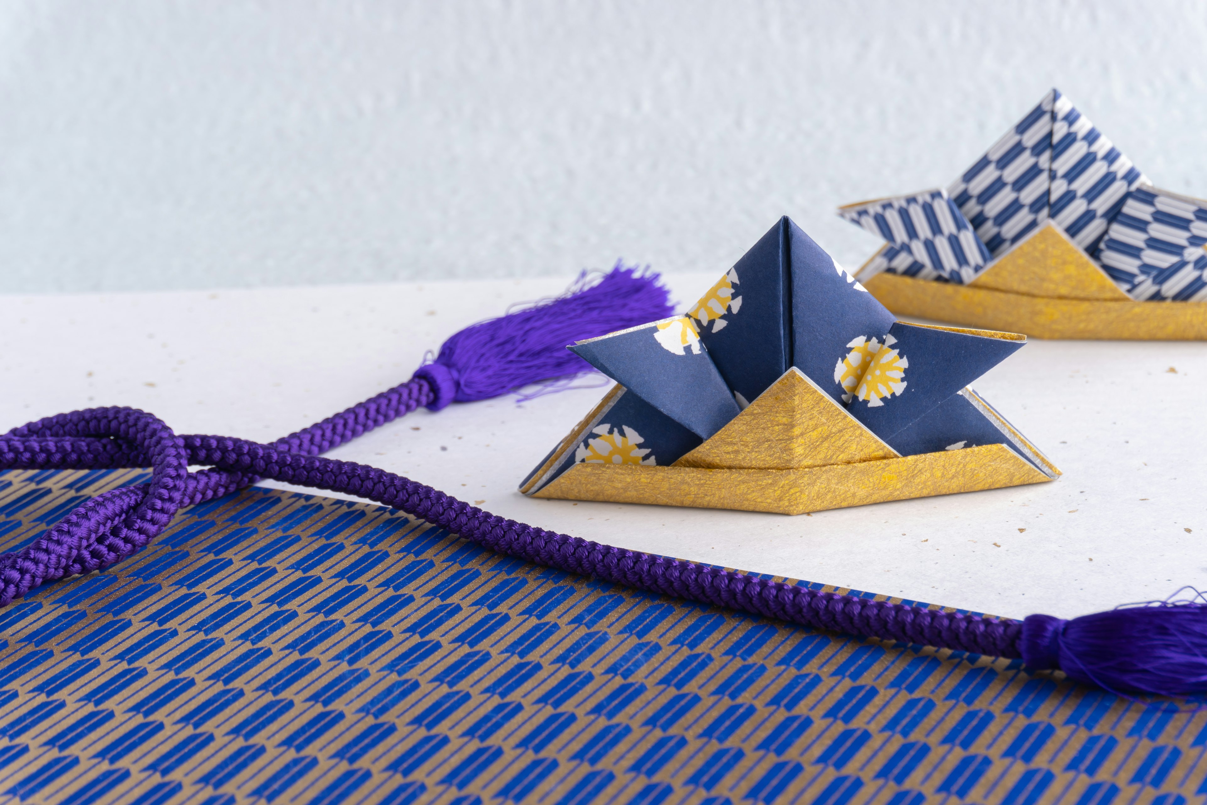 Barche di origami con motivi blu e bianchi e corde viola su un tavolo