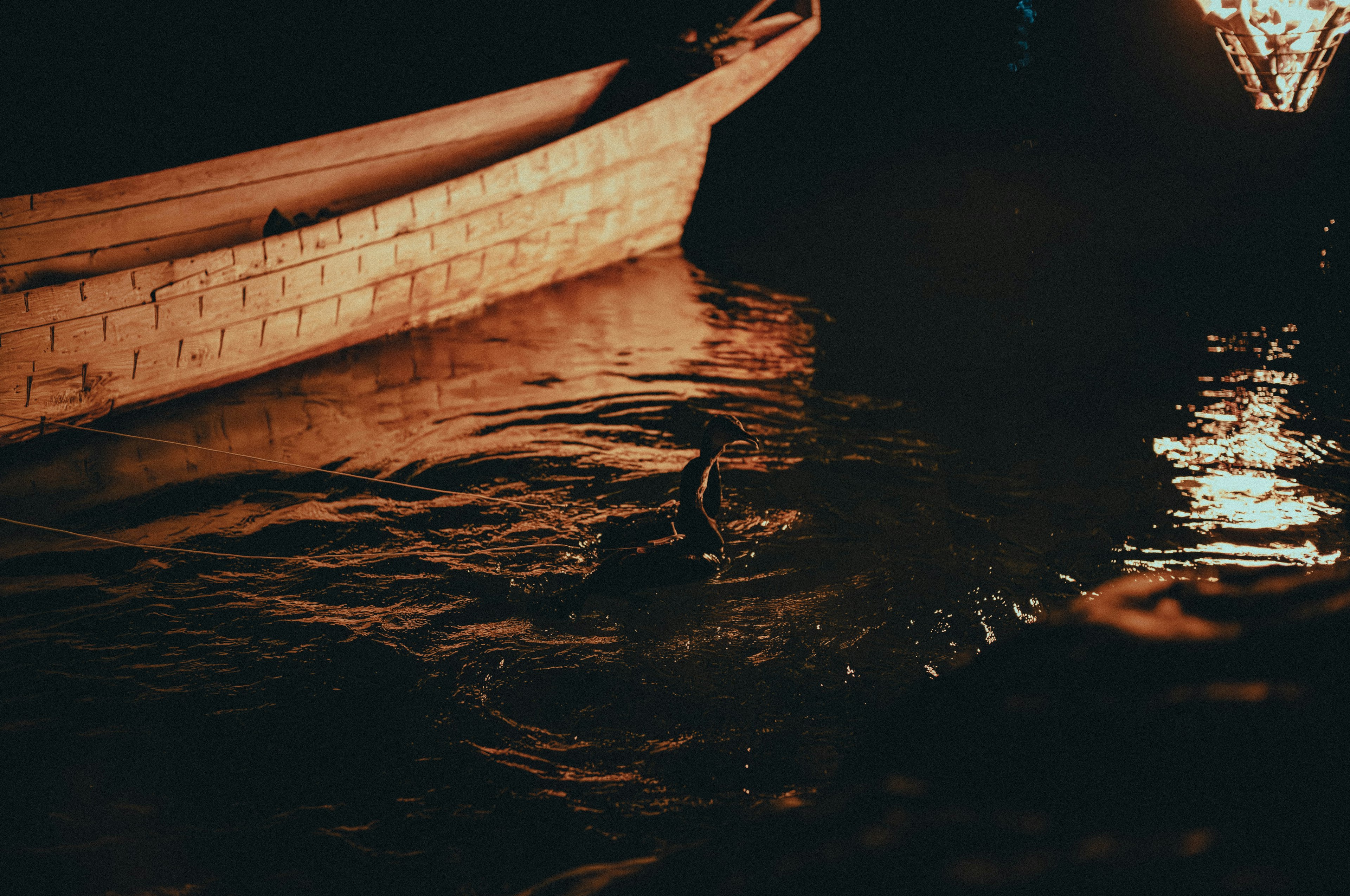 Silhouette d'un petit bateau avec des reflets sur l'eau la nuit