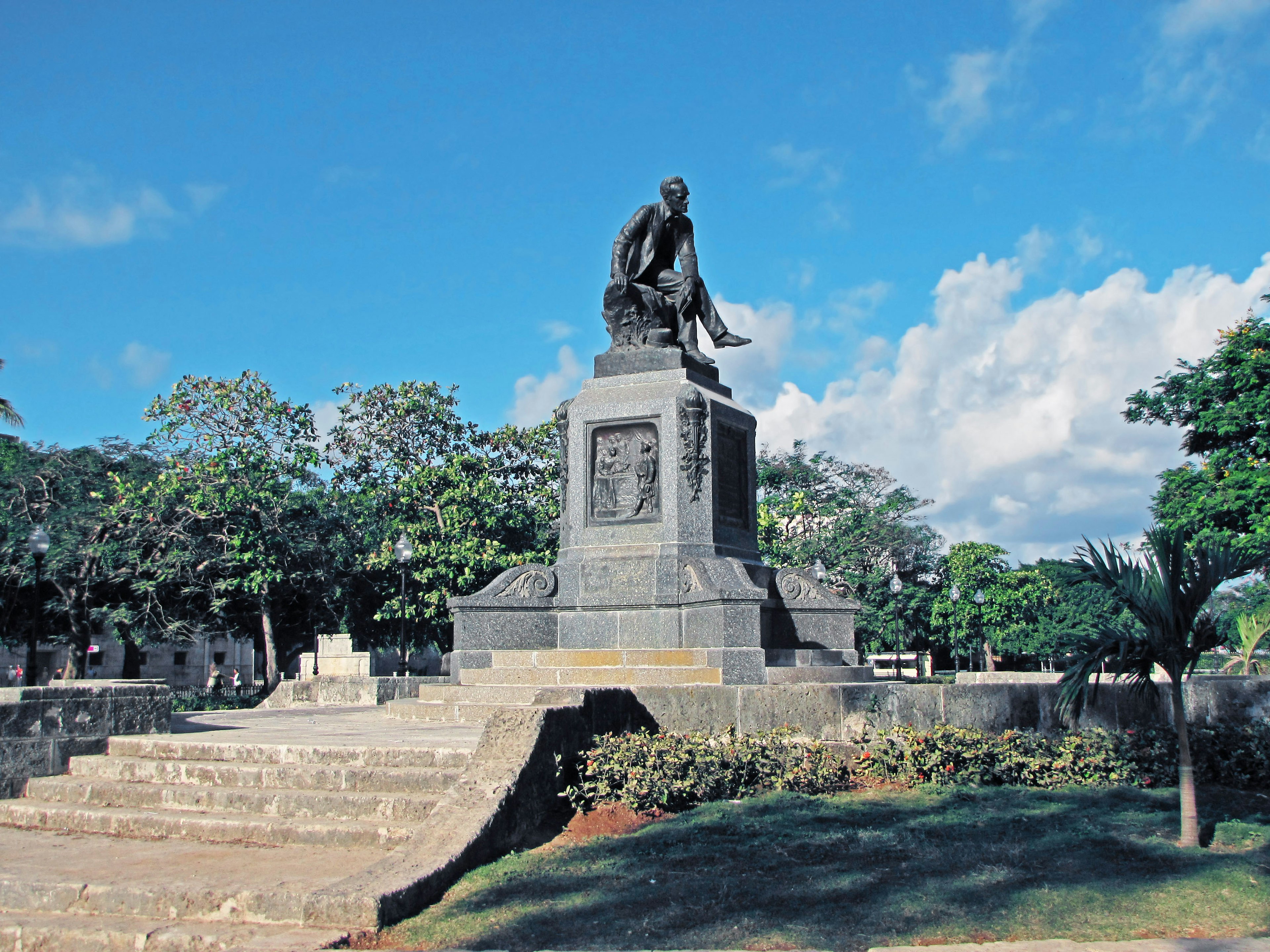 Monument under a blue sky surrounded by greenery