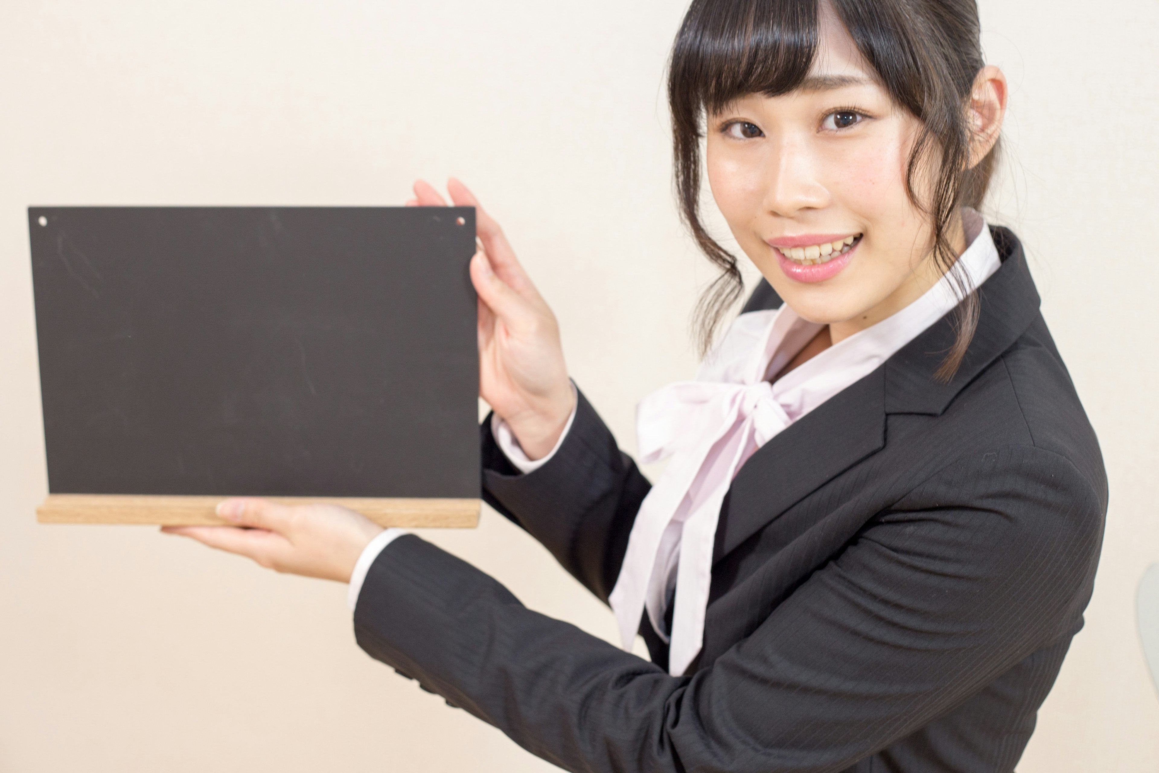 A smiling woman in a suit holding a blackboard