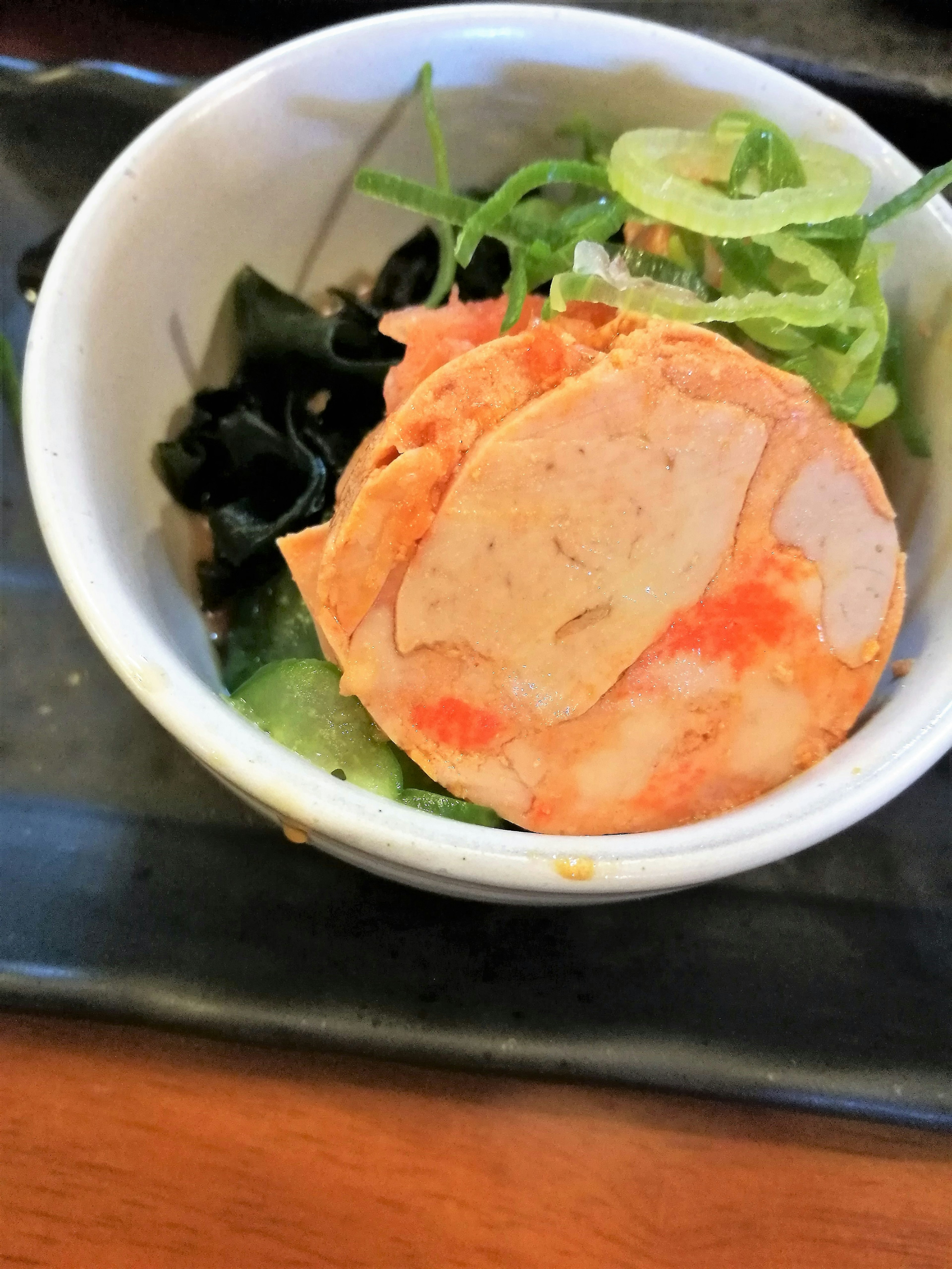 Gâteau de poisson tranché servi avec des algues et des légumes verts