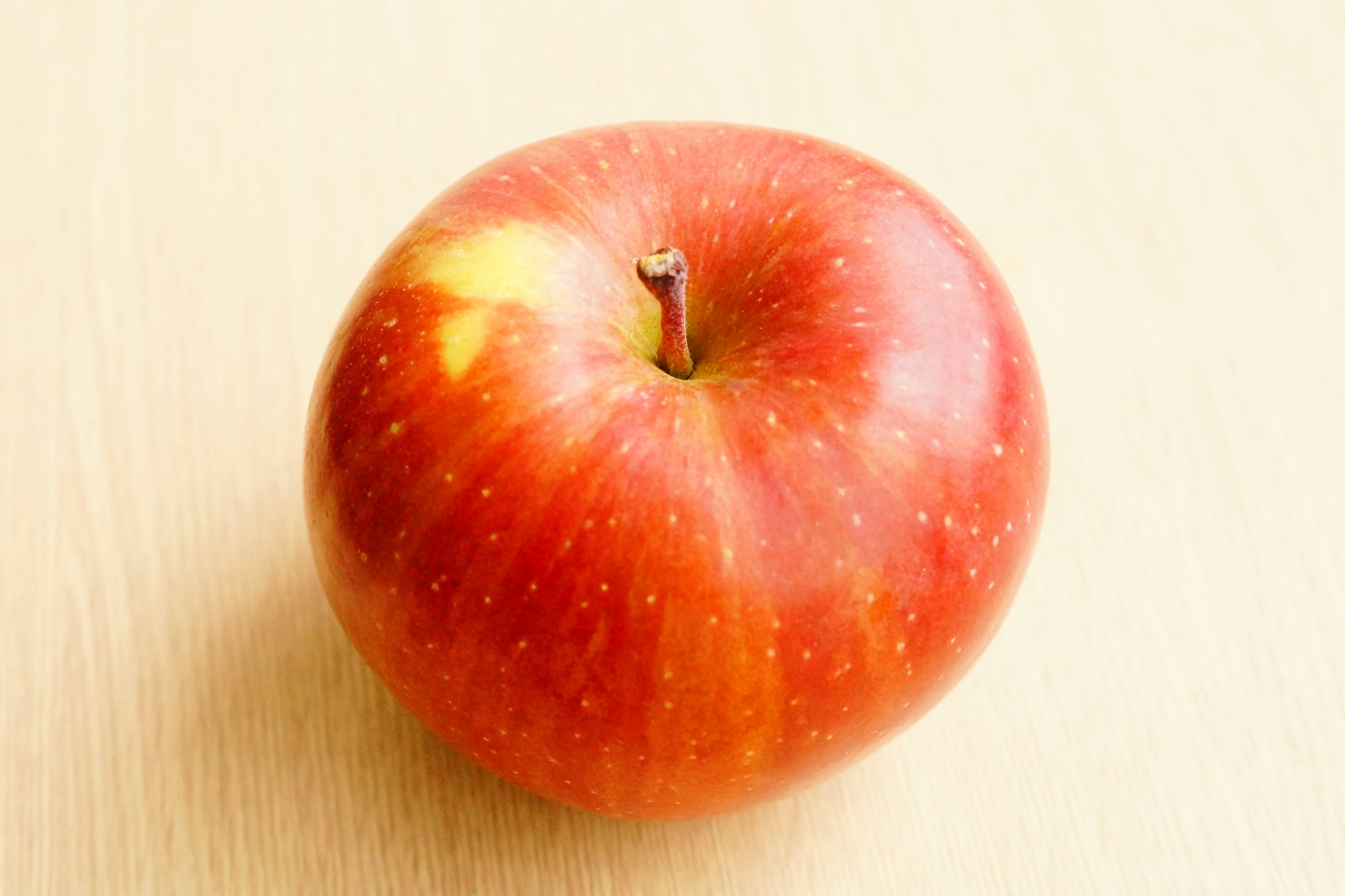 A red apple resting on a wooden table