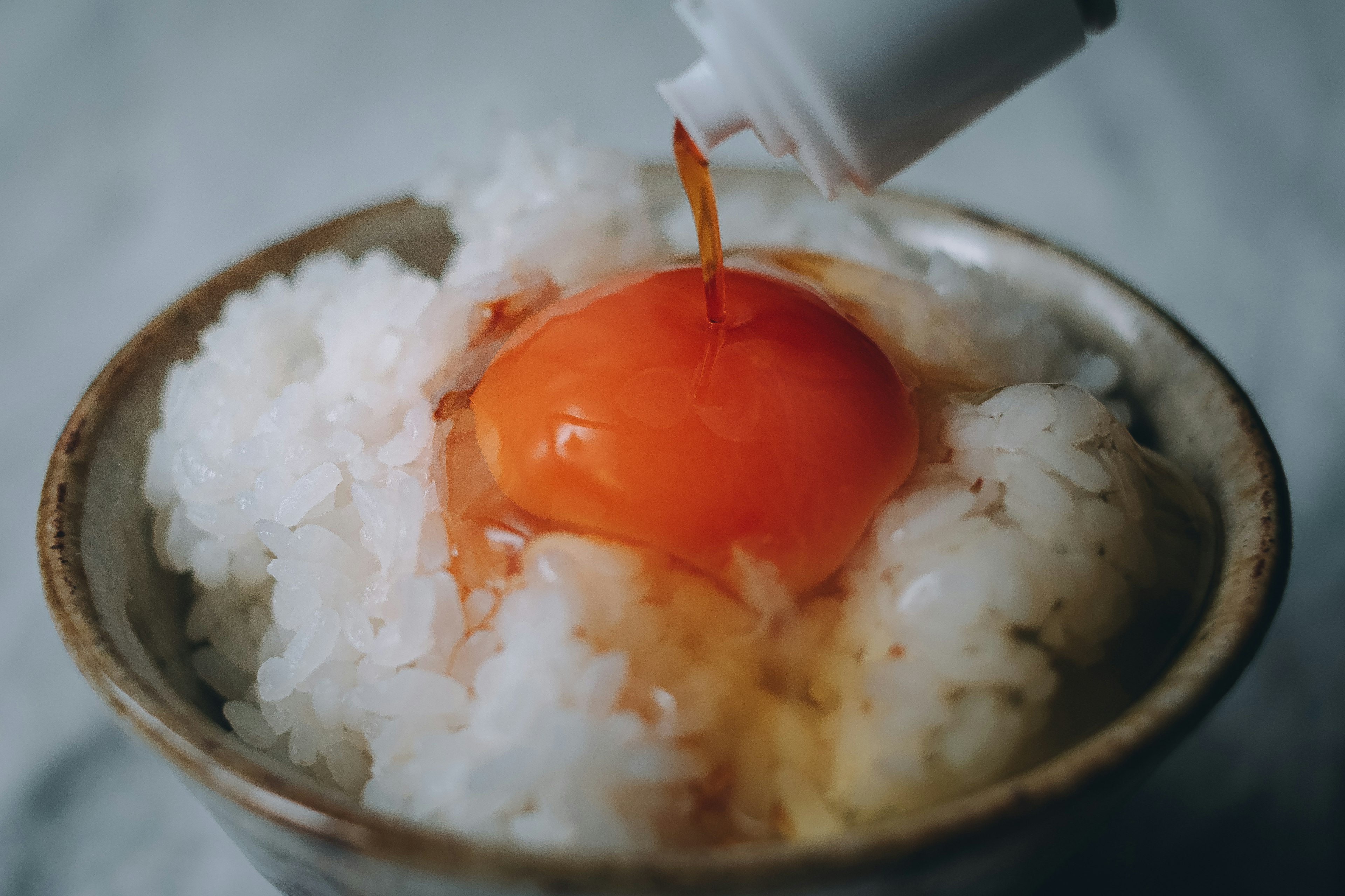 Un bol de riz surmonté d'un jaune d'œuf cru arrosé de sauce soja