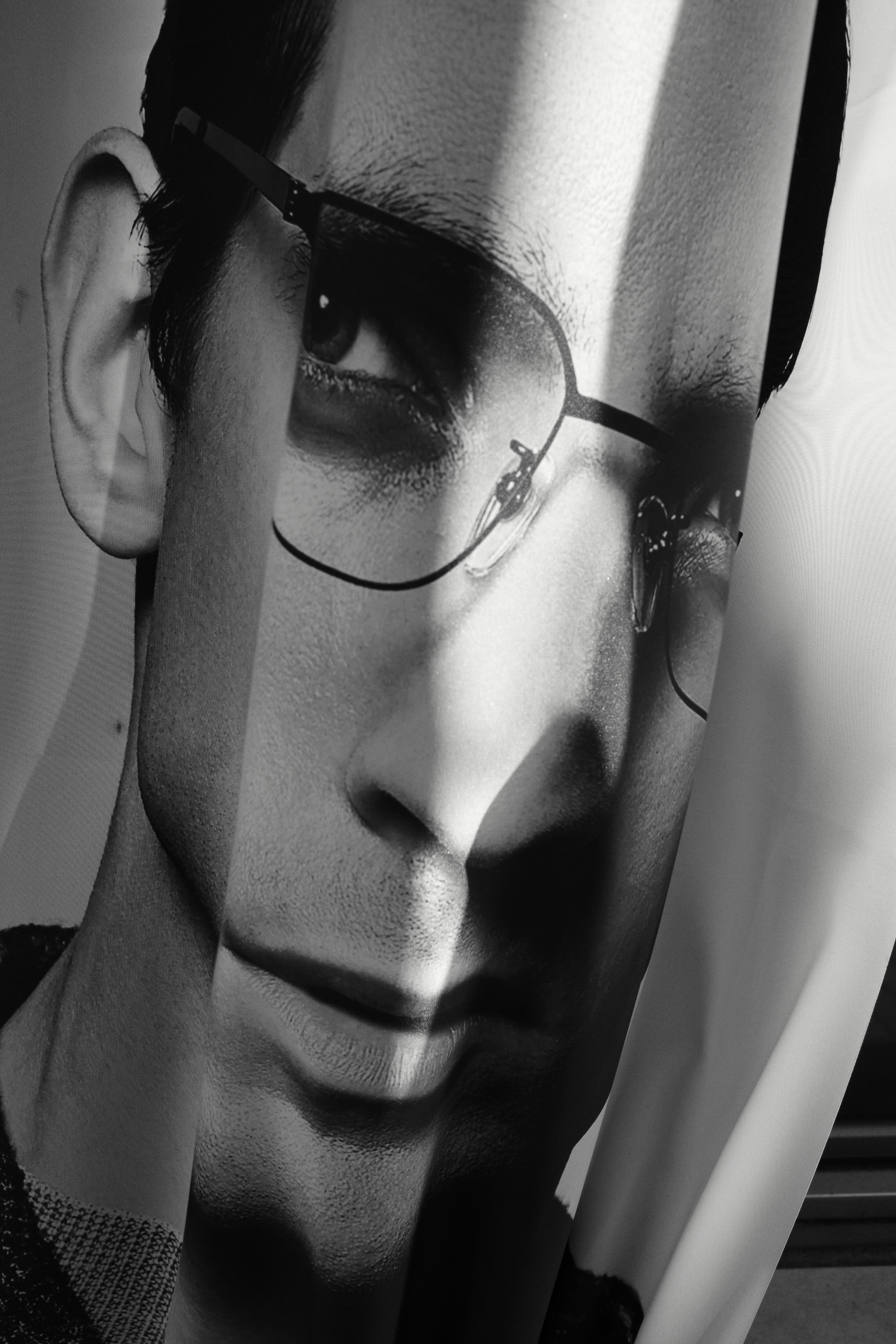 Partial image of a face in black and white featuring a man wearing glasses