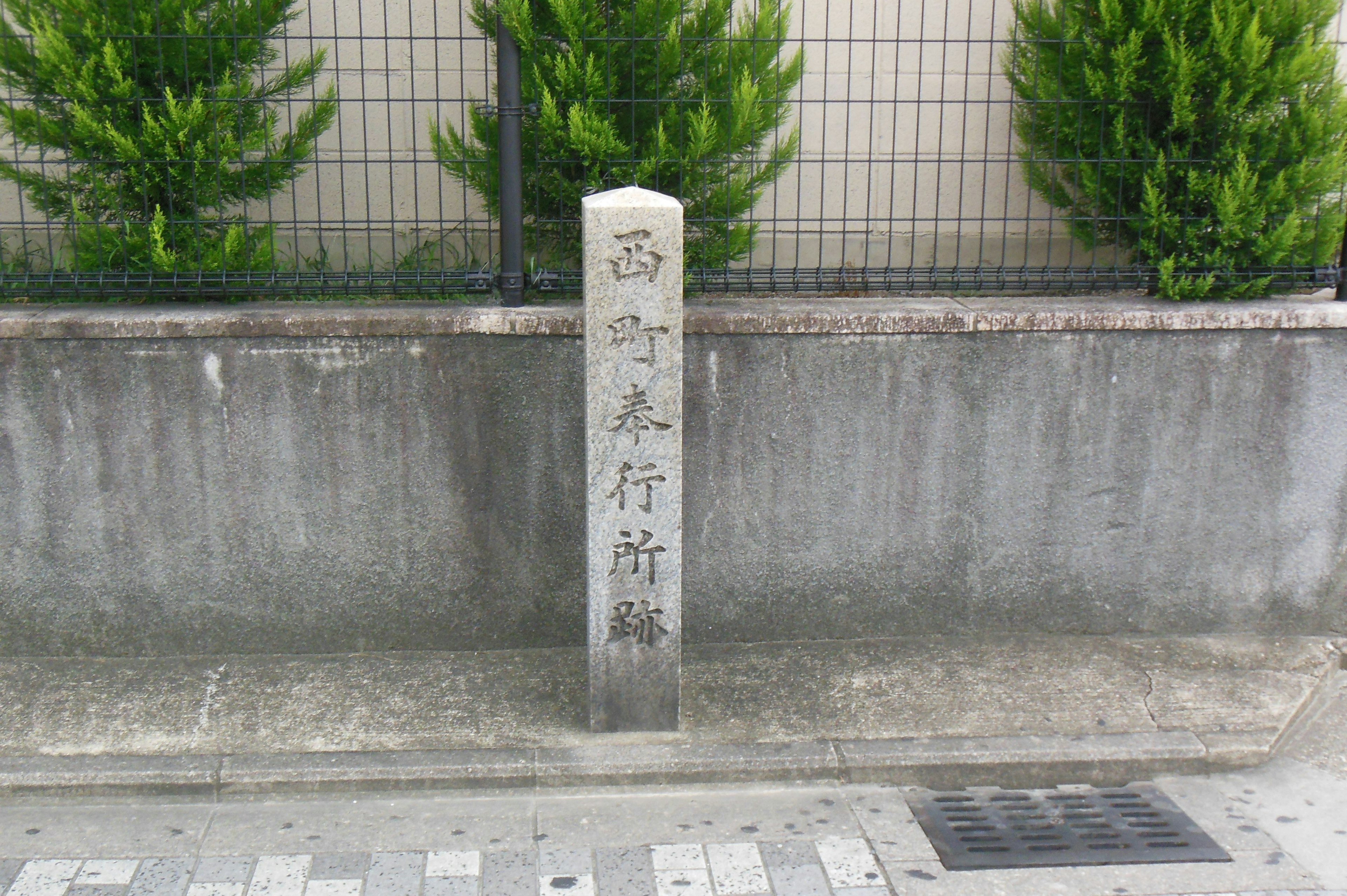 Monumento de piedra con caracteres grabados y plantas verdes alrededor