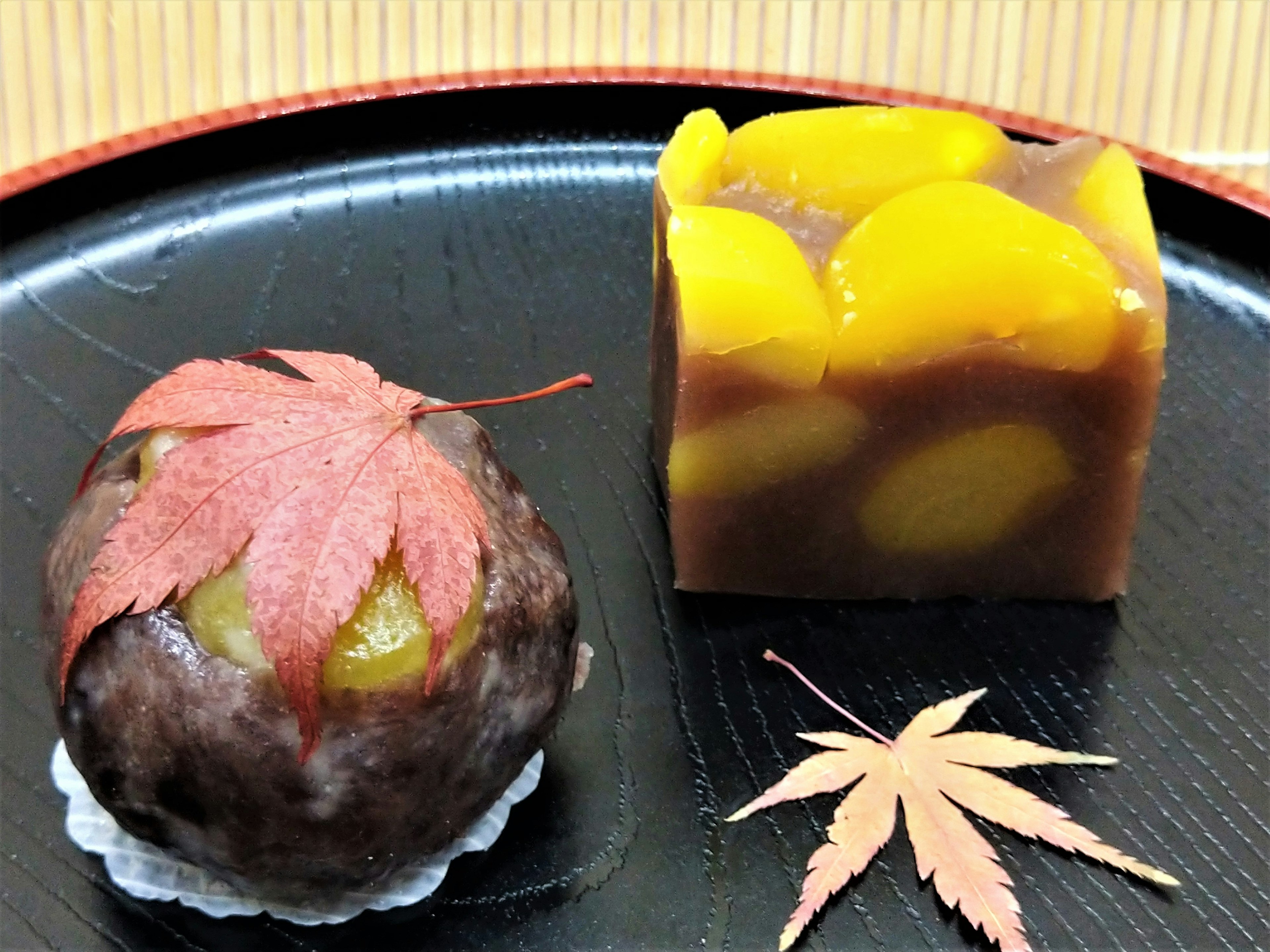 Autumn Japanese sweets display featuring a chestnut confection topped with a red maple leaf and a translucent jelly with chestnuts